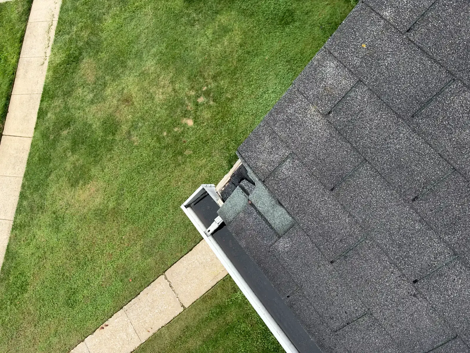 Asphalt shingle repair at the corner where the roof meets the gutter