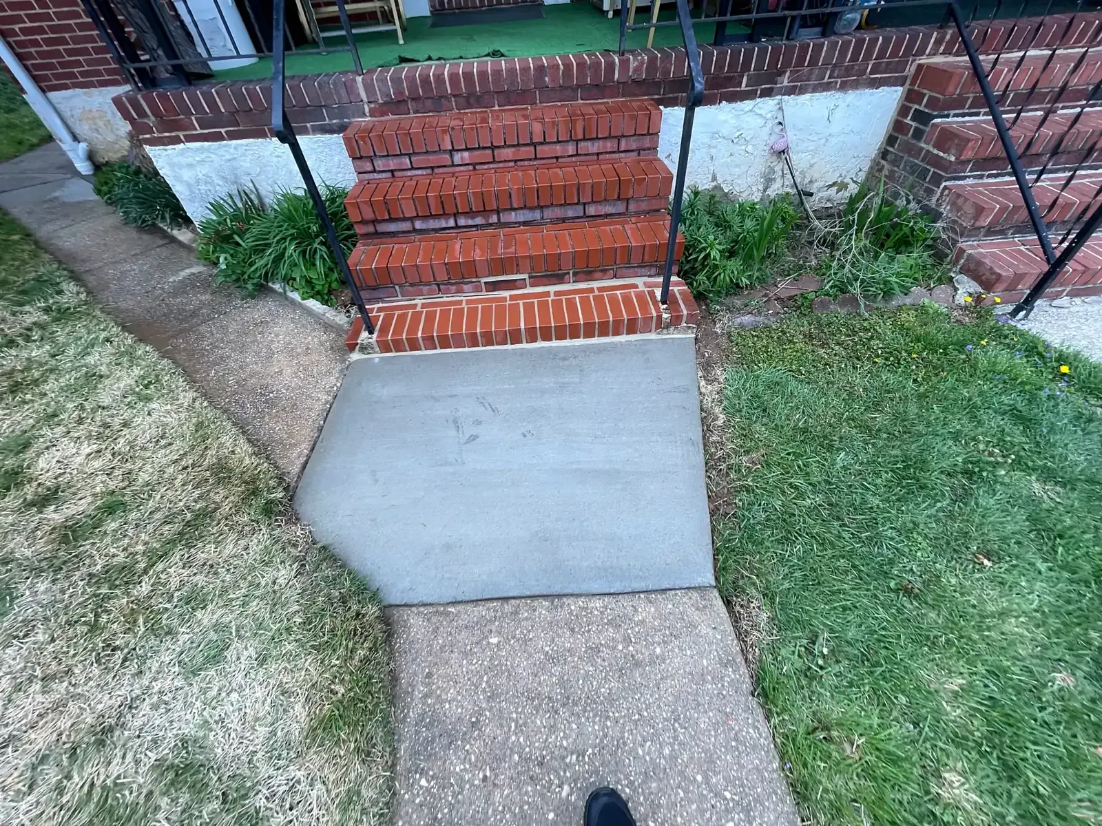 New concrete sidewalk slab poured at the foot of brick front steps
