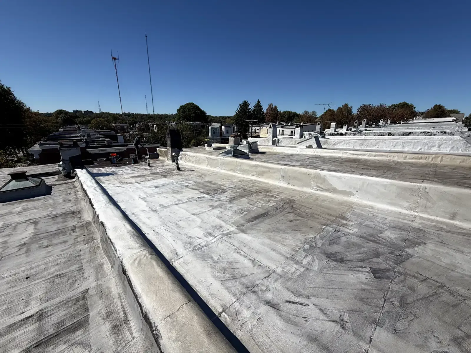 A row of rowhouse flat roofs with a fresh silver coating