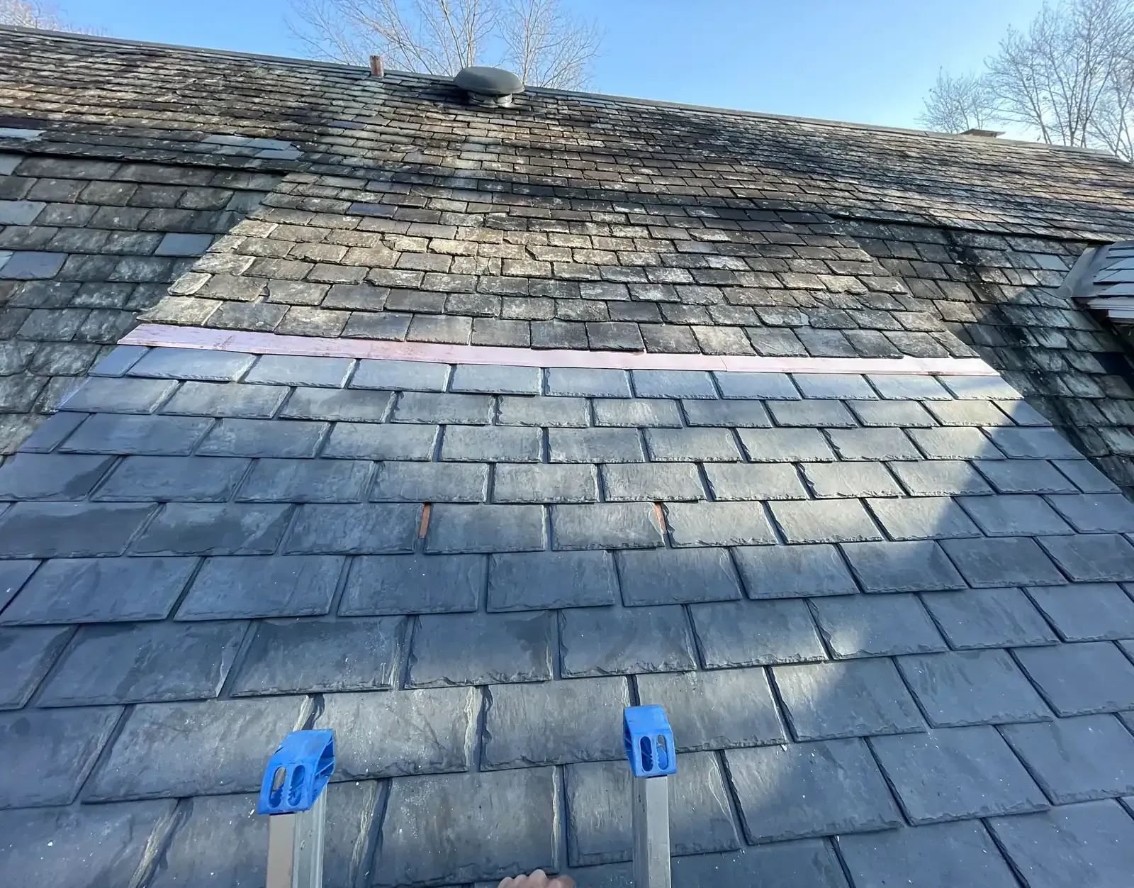 Slate roof with new copper transition metal where we reinstalled leaking synthetic slates