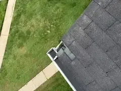 Asphalt shingle repair at the corner where the roof meets the gutter