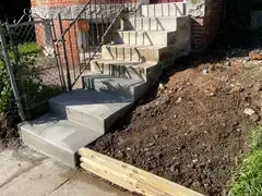 New concrete steps poured below the original stone steps of a rowhouse