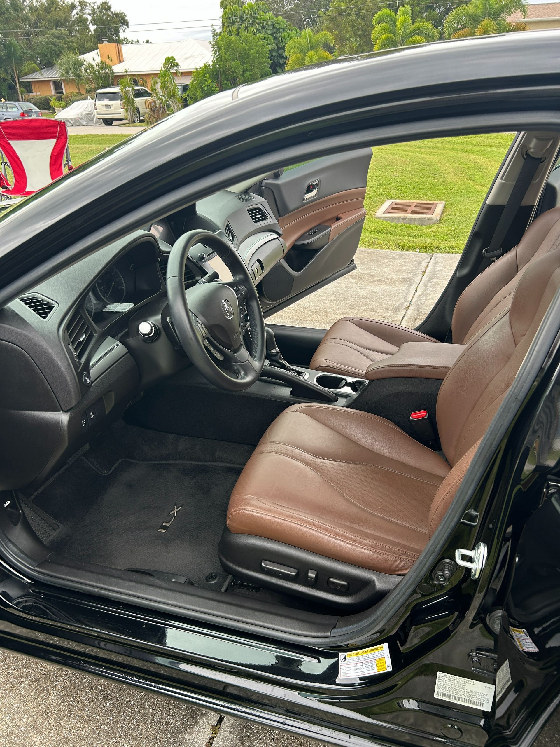 Open car door showing brown leather driver's seat and steering wheel interior.