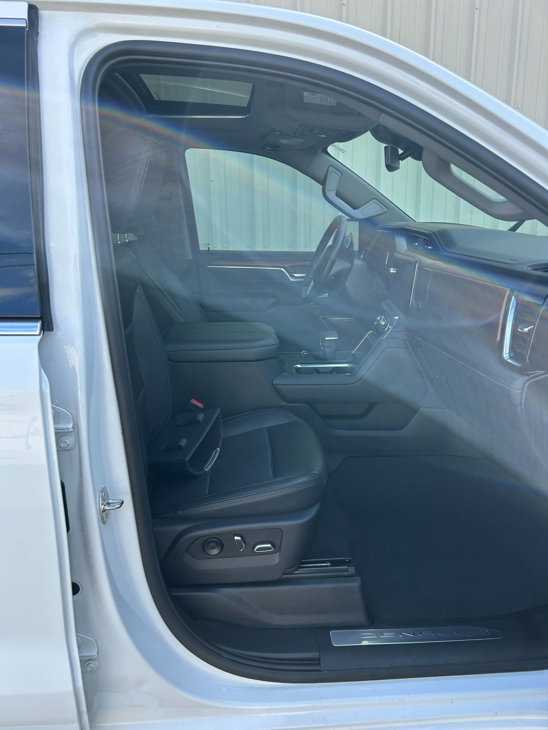 Open car door revealing a black leather driver’s seat and dashboard interior