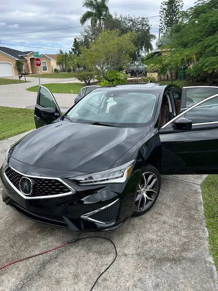 Black Acura sedan parked in a driveway with both front doors open