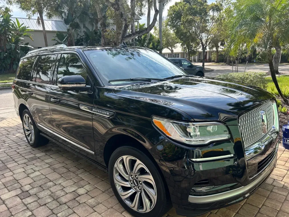 Black SUV parked on a brick driveway under trees, front-left view