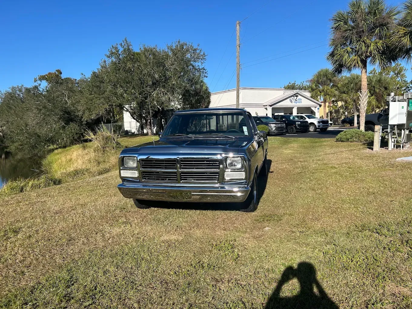 Black pickup truck parked on a grassy lawn near a house under a clear sky