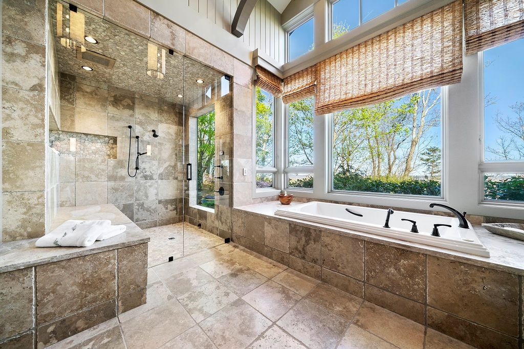 A bathroom with a tub , shower , and large windows.