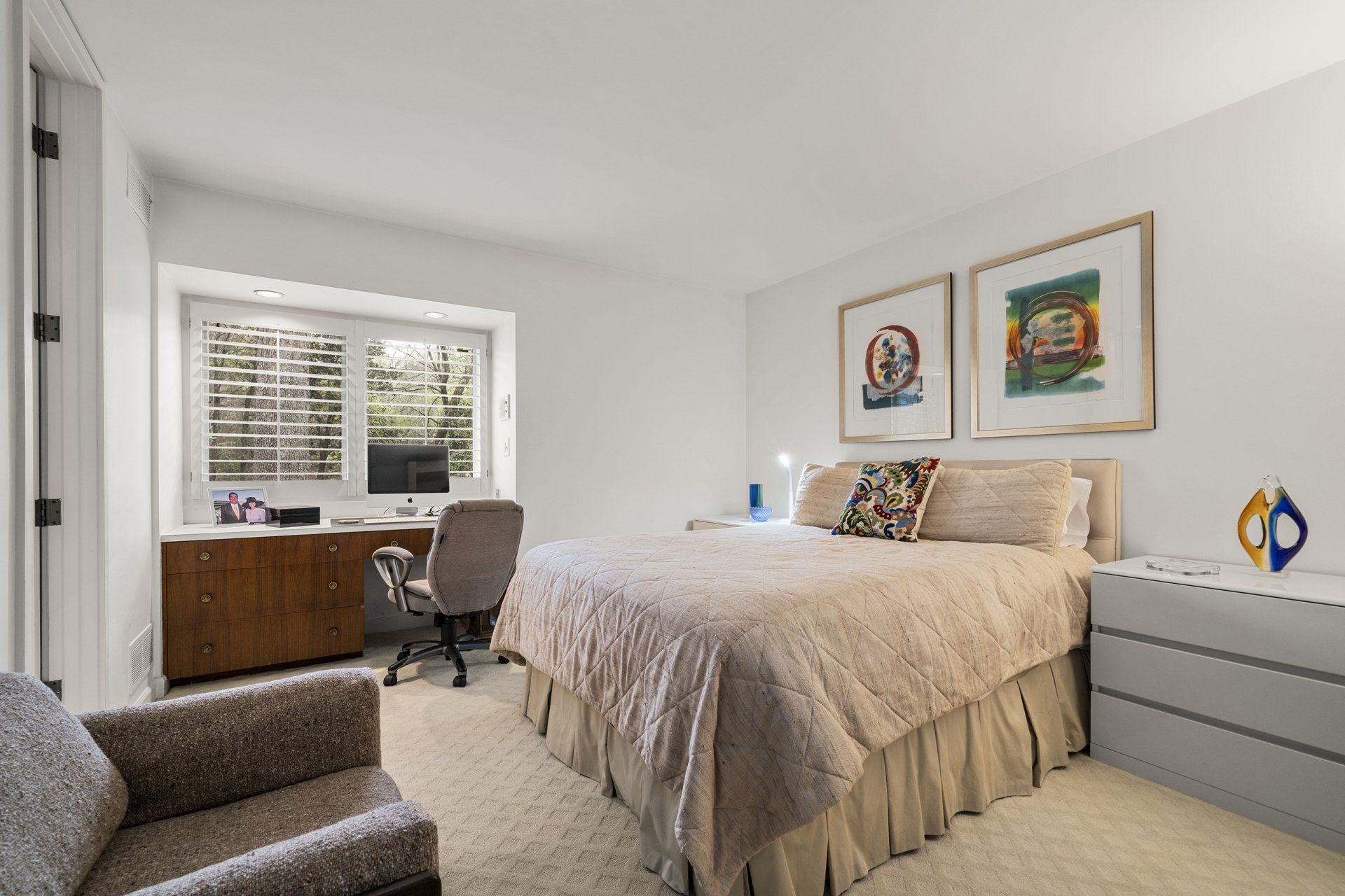 A bedroom with a large bed , chair , desk and window.