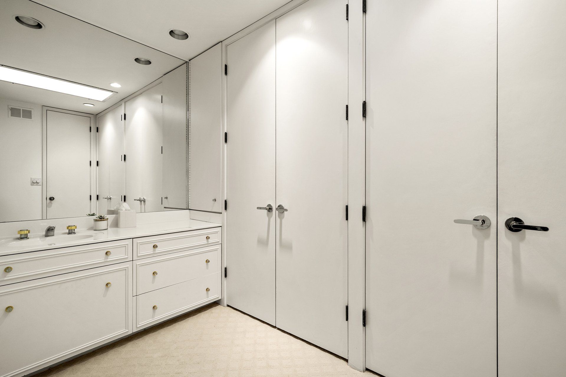 A bathroom with white cabinets and a large mirror