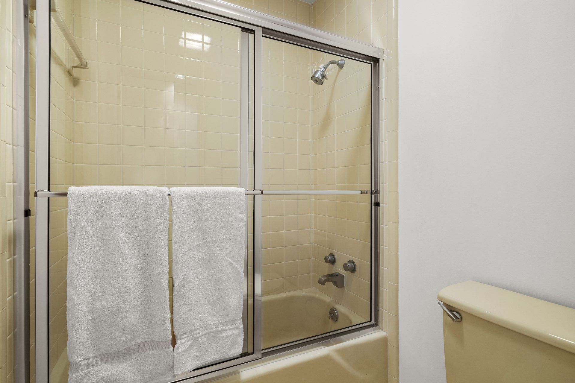 A bathroom with a sliding glass shower door and a bathtub.