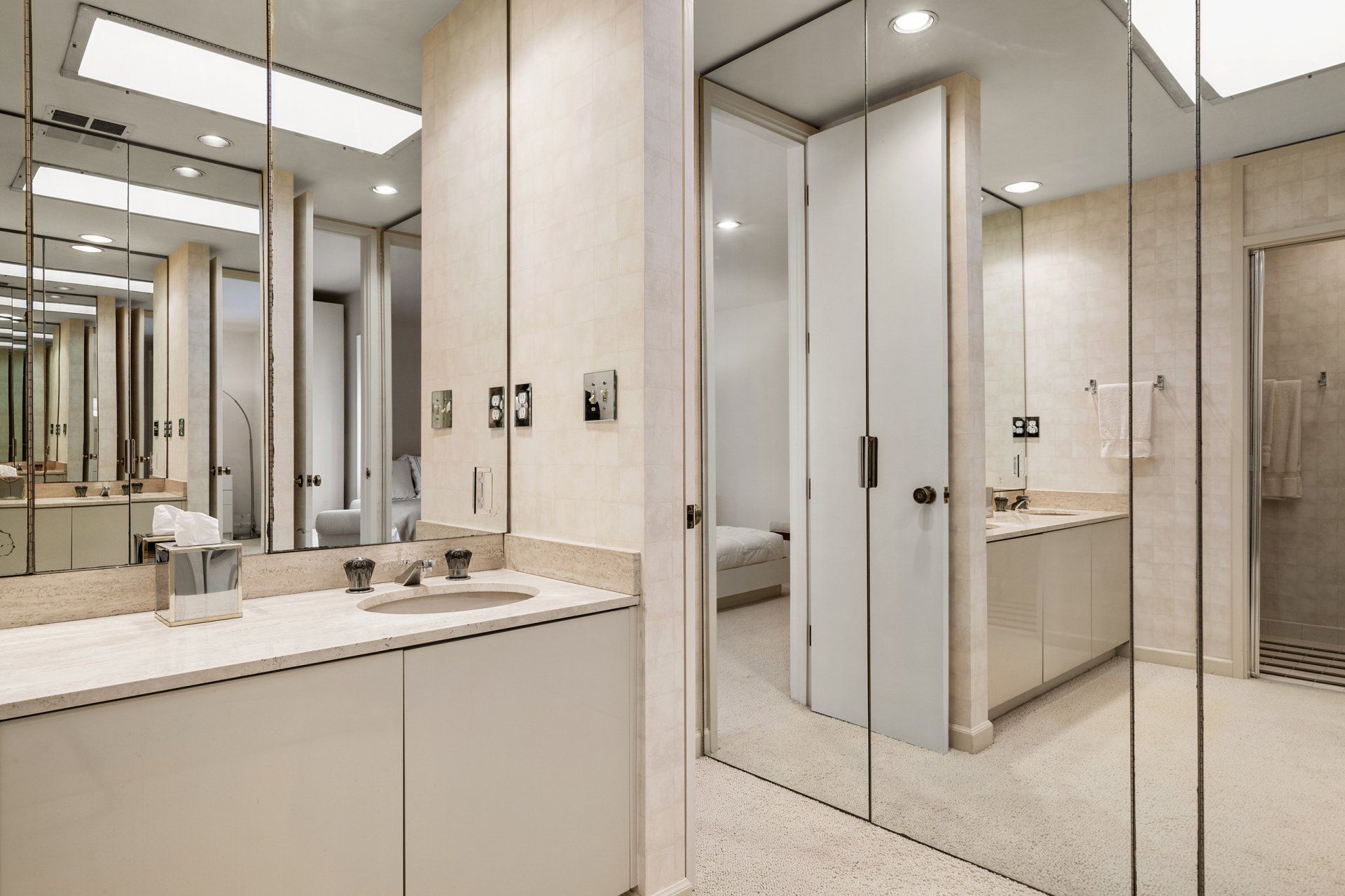 A bathroom with a sink , mirrors and a walk in shower.