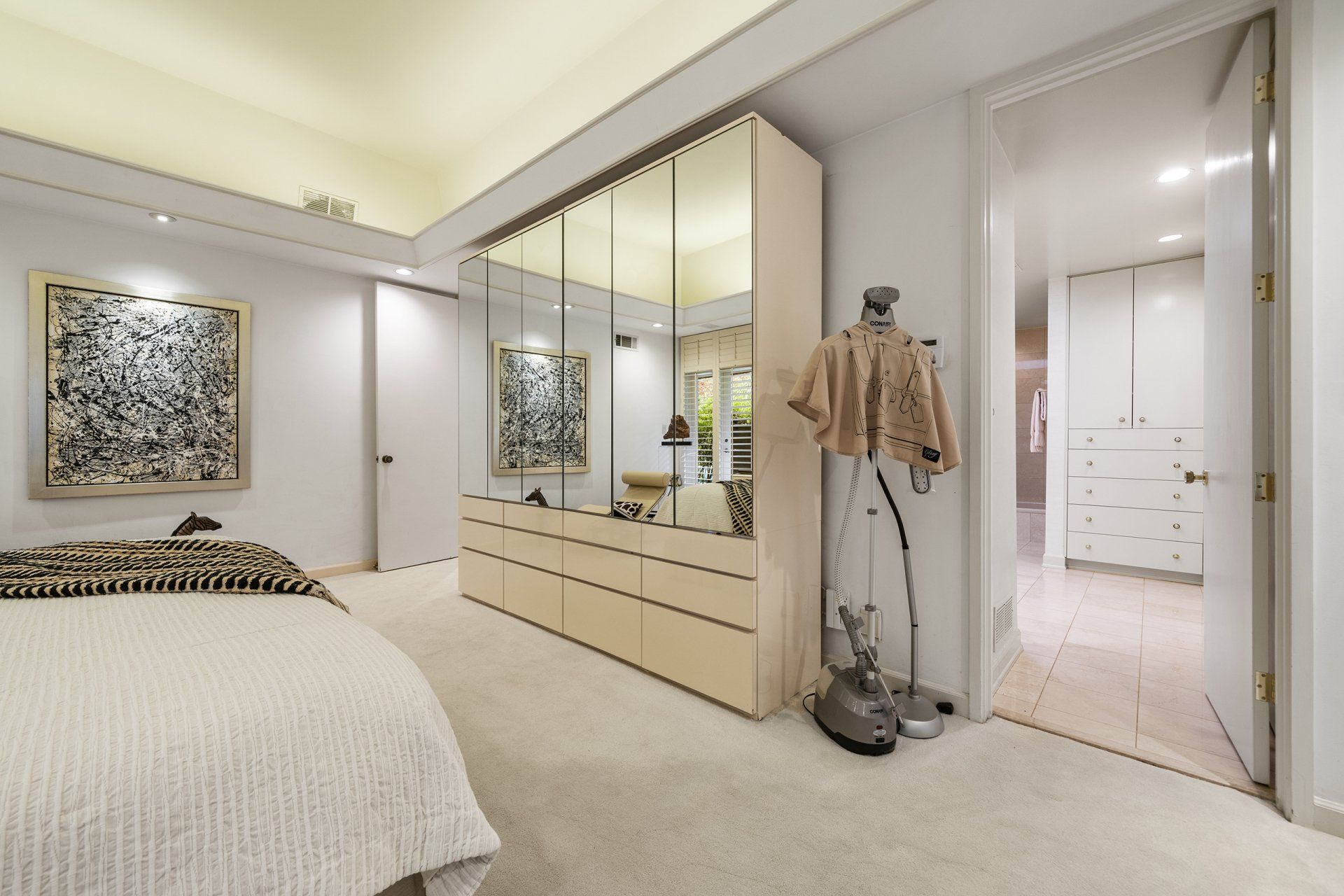 A bedroom with a bed , dresser , mirrors and a mannequin.