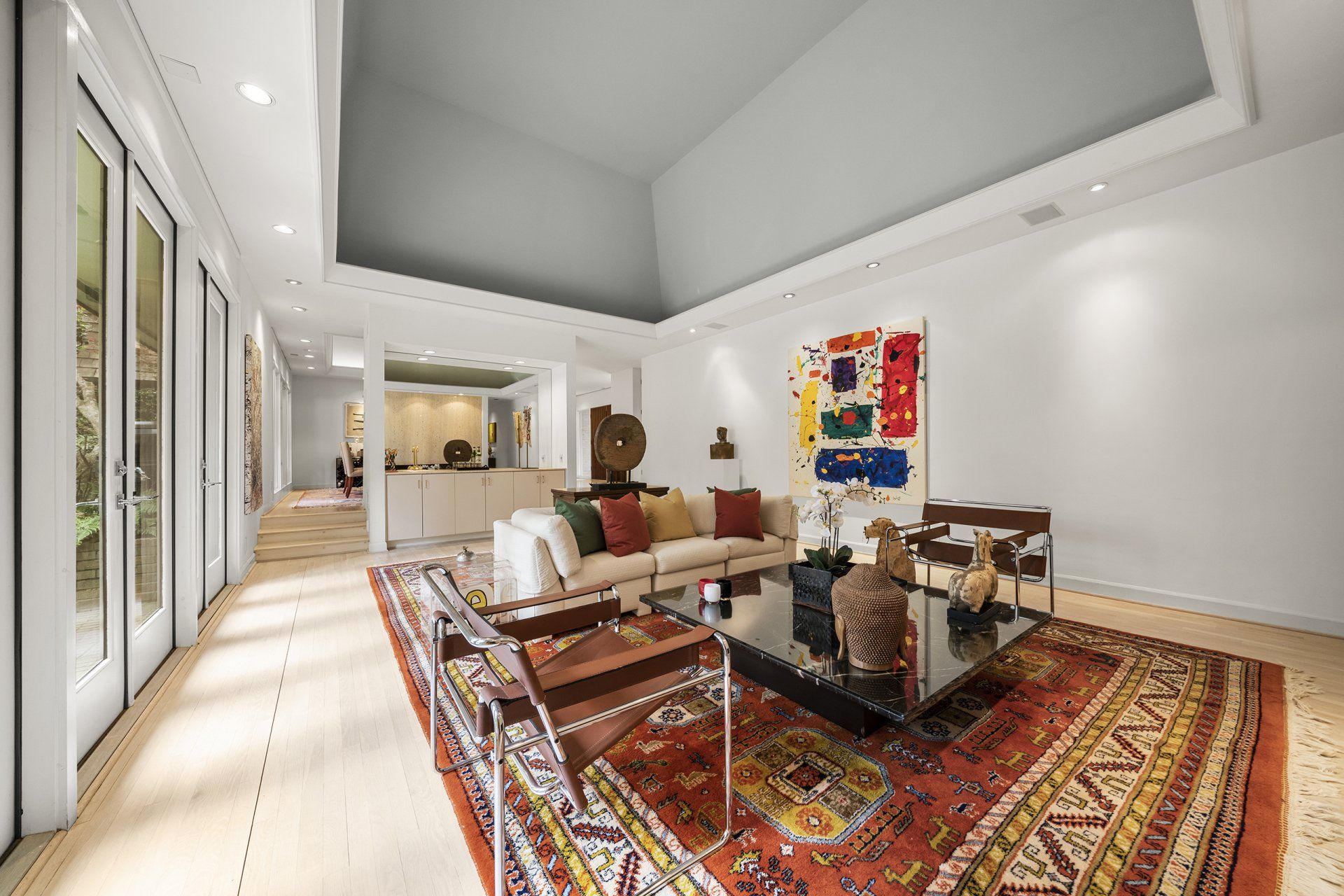 A living room with a couch , chairs , coffee table and rug.