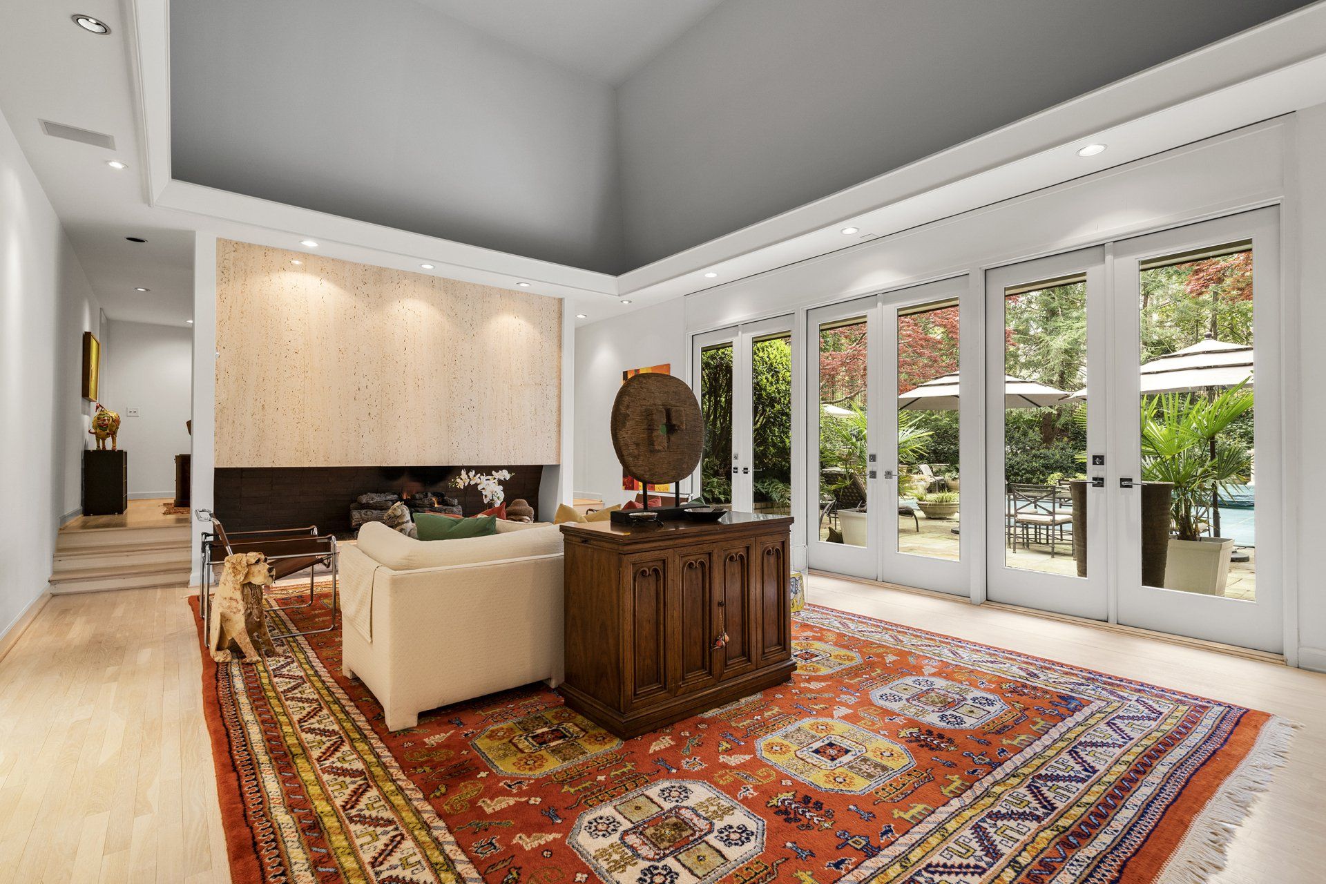 A living room with a rug , couch , table and lots of windows.