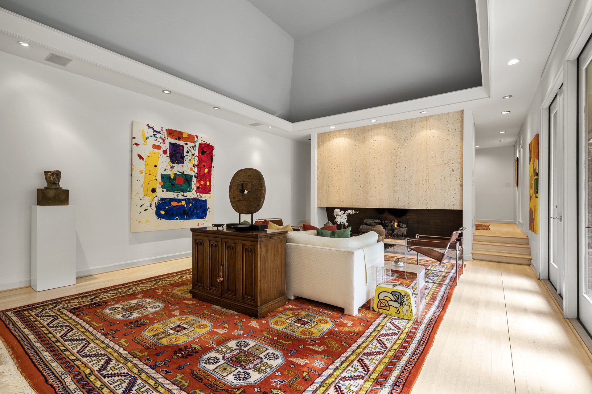 A living room with a rug , couch , fireplace and painting on the wall.