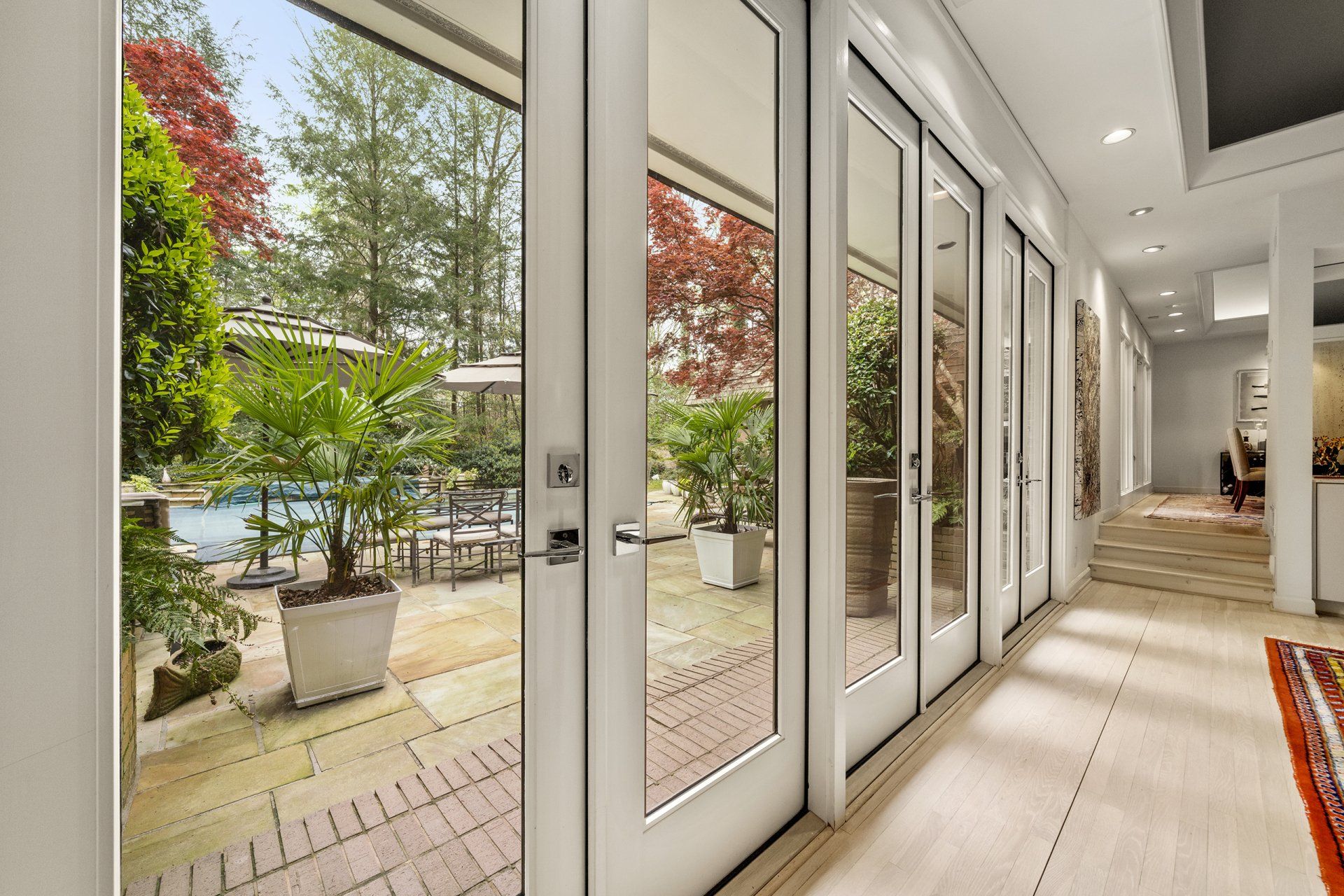 A hallway with sliding glass doors leading to a patio and a pool.