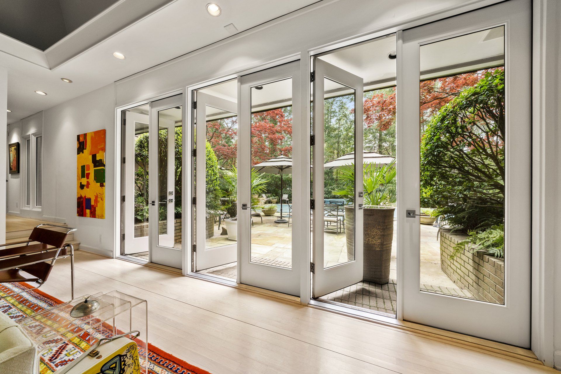 A living room with a lot of windows and doors leading to a patio.