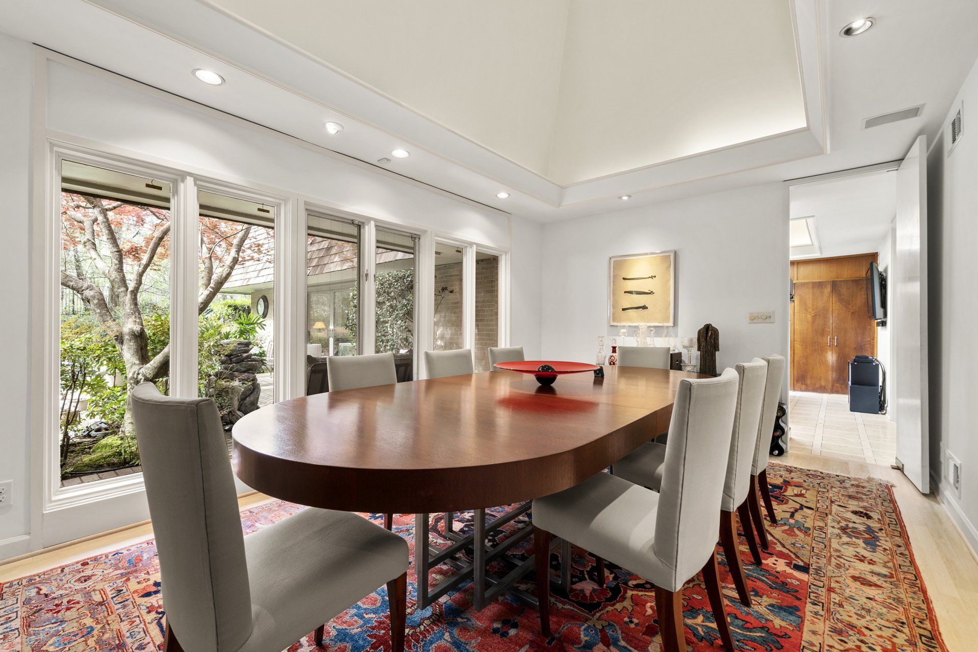 A dining room with a long table and chairs and a rug.