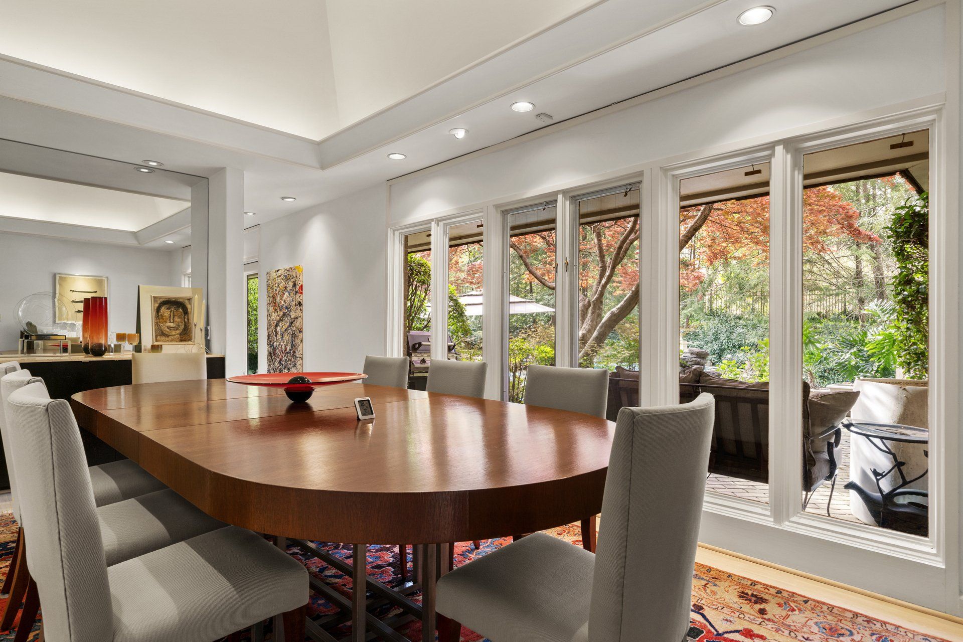 A dining room with a large table and chairs and lots of windows.
