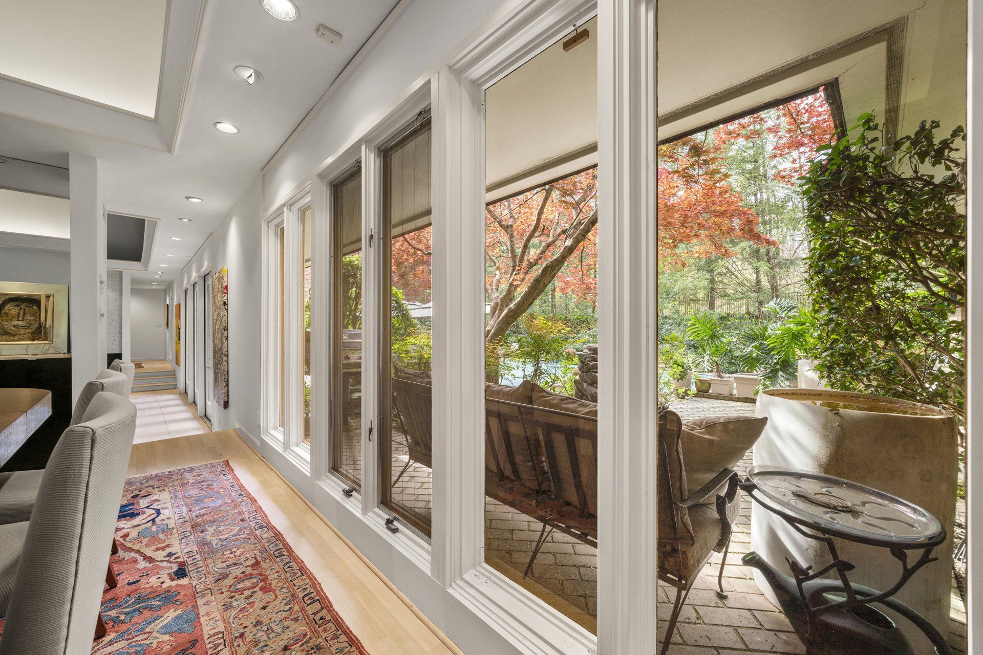 A long hallway in a house with lots of windows and a rug.