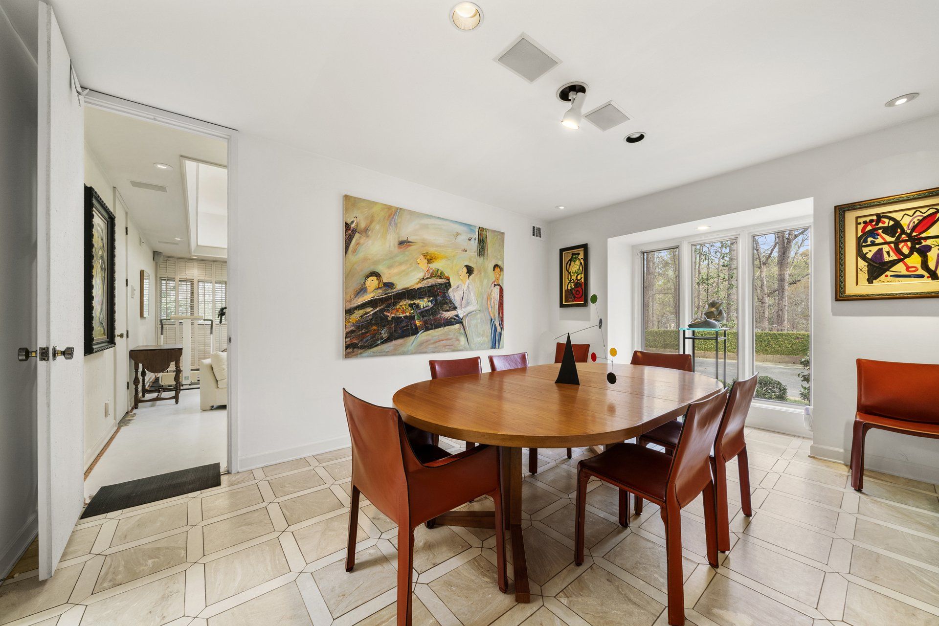 A dining room with a round table and chairs and paintings on the wall.