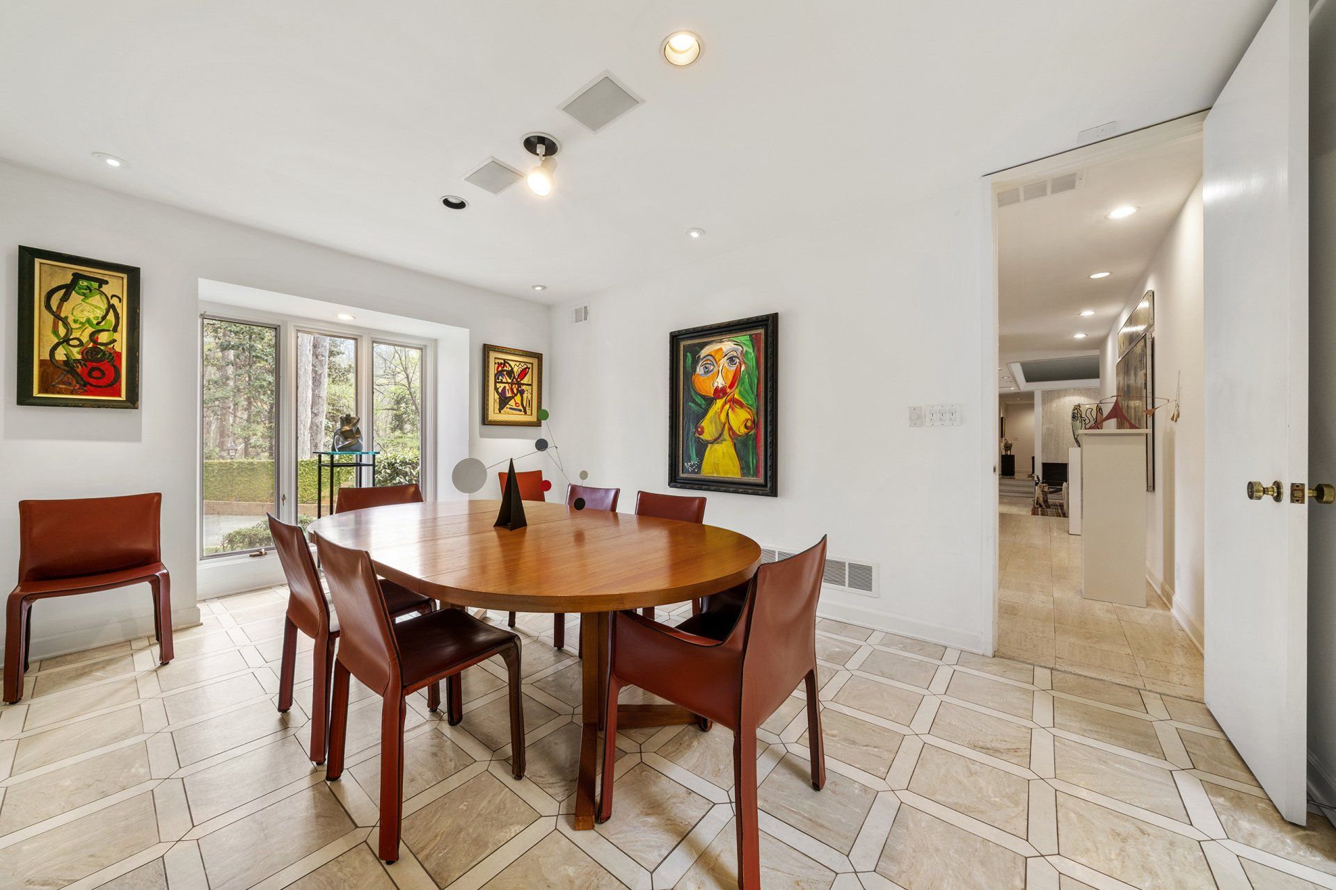 A dining room with a round table and chairs and paintings on the wall.
