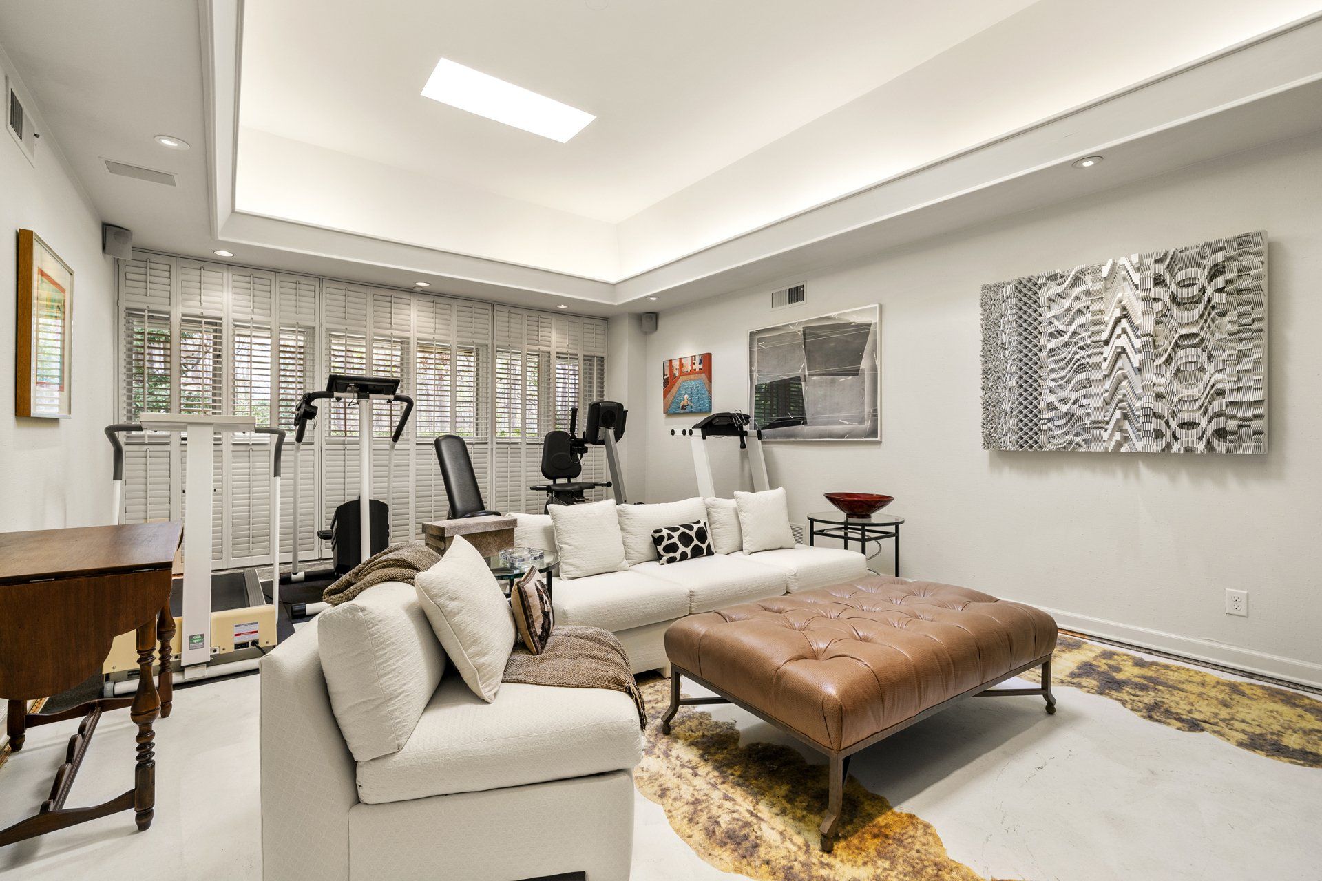 A living room with a couch , ottoman , and treadmill.