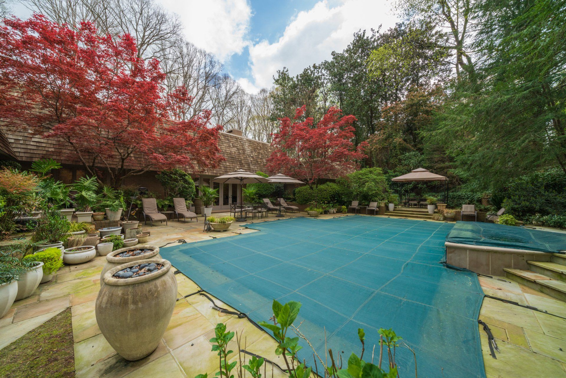 A large swimming pool with a blue cover in the backyard of a house.