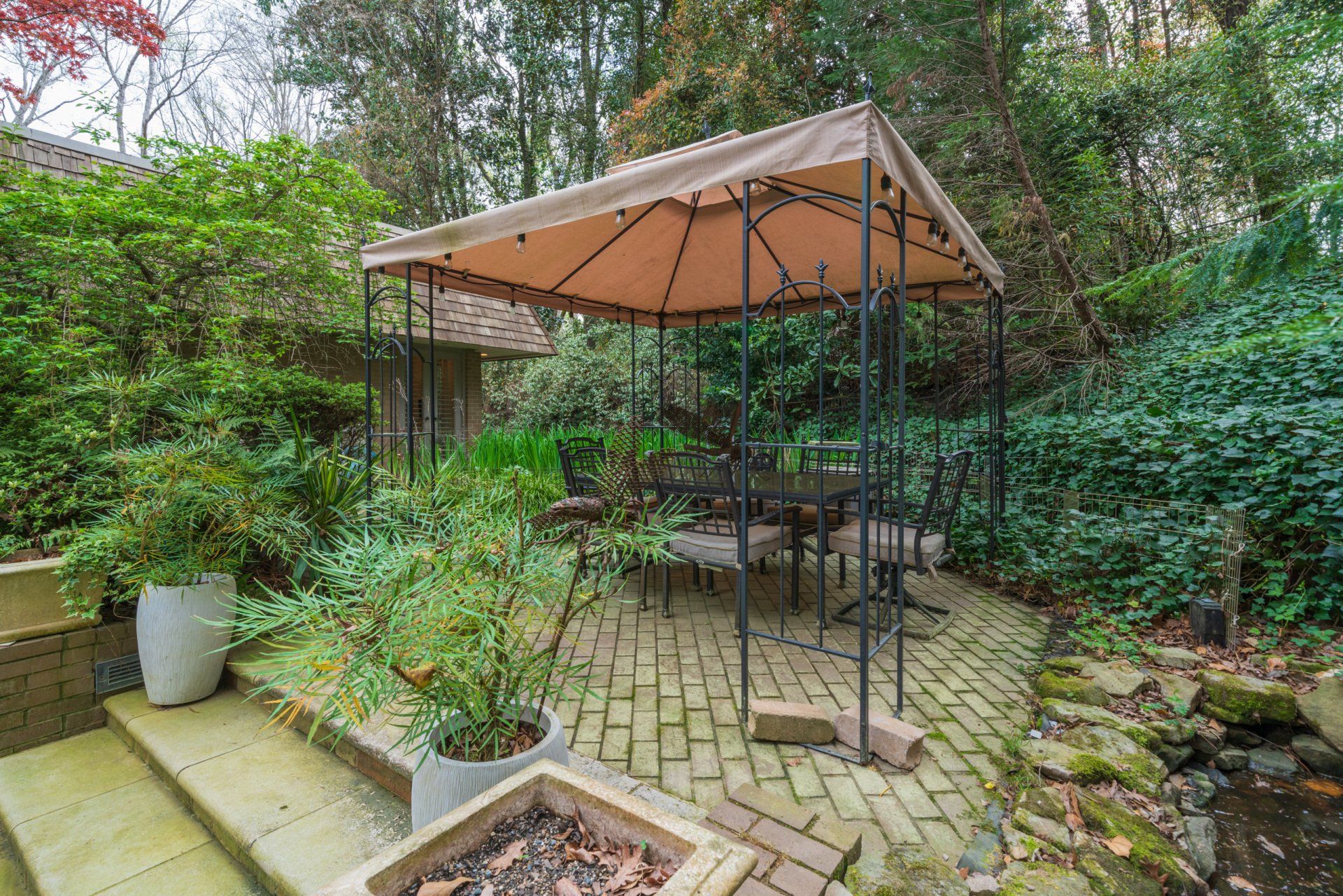 There is a gazebo in the backyard with a table and chairs underneath it.