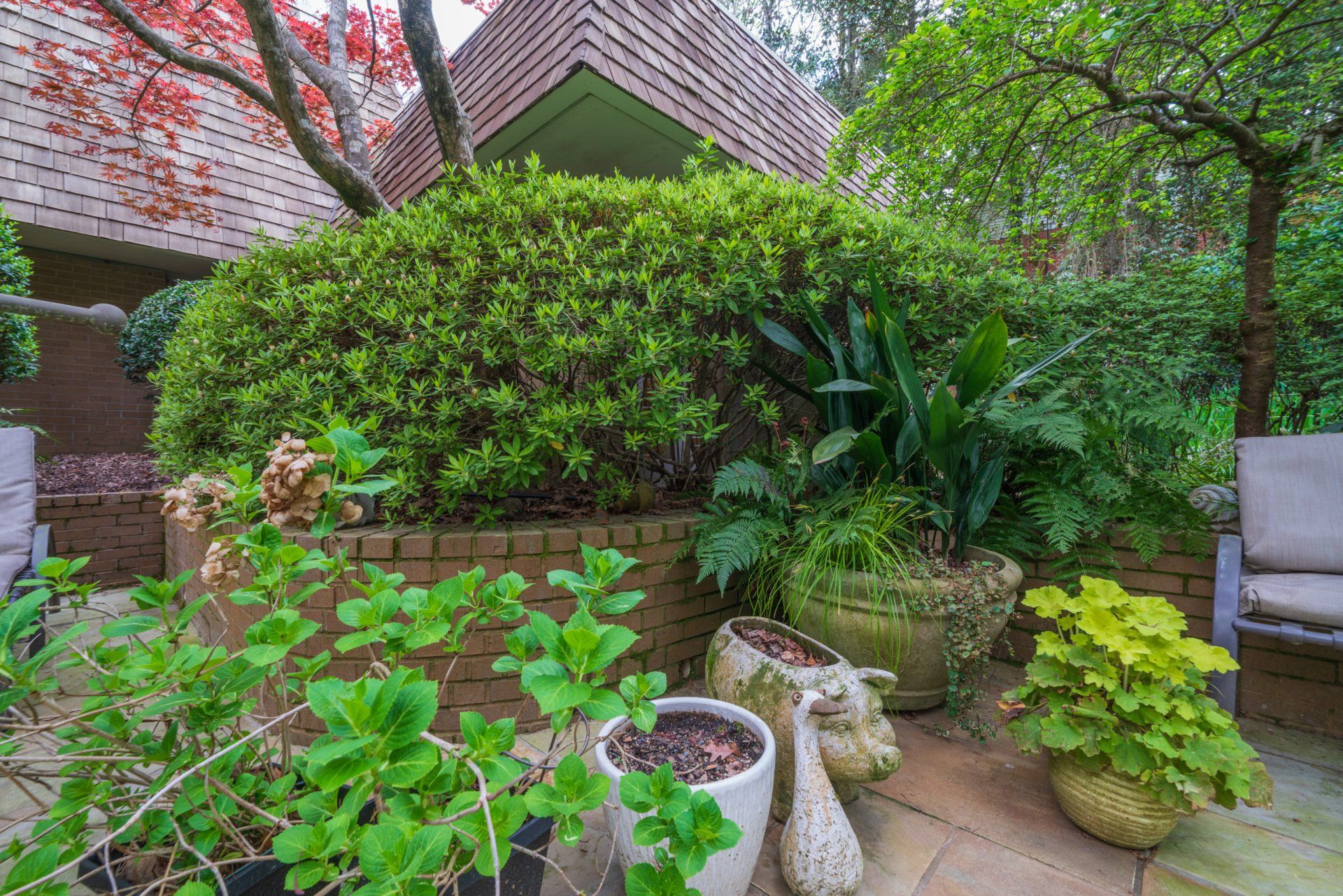 A patio with lots of potted plants and a brick wall.