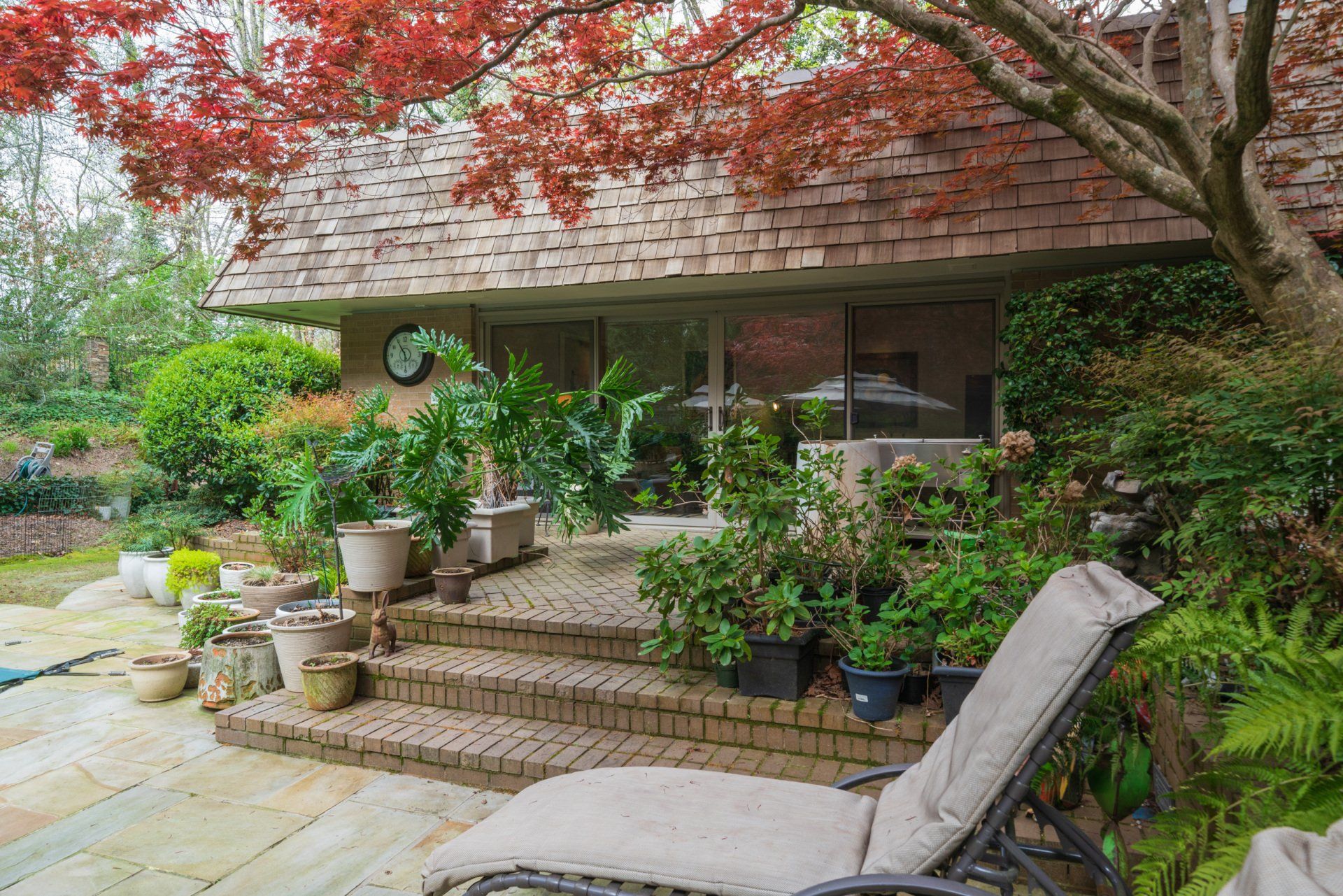 A patio with chairs and potted plants in front of a house.