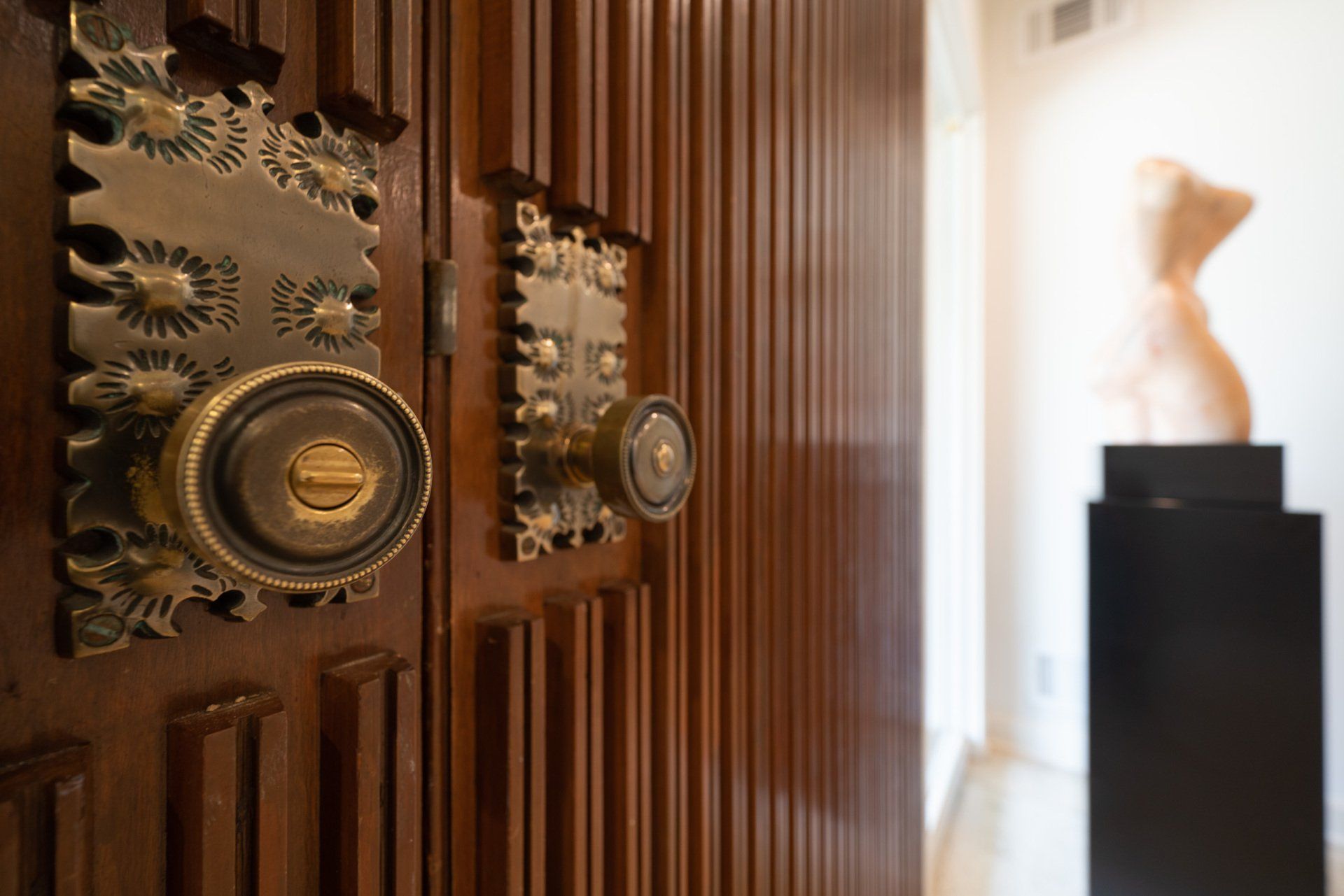 A close up of a door with a statue in the background.