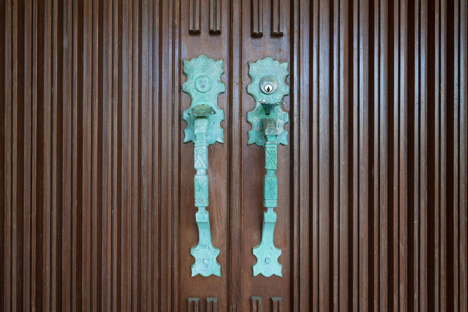 A close up of two door handles on a wooden door.