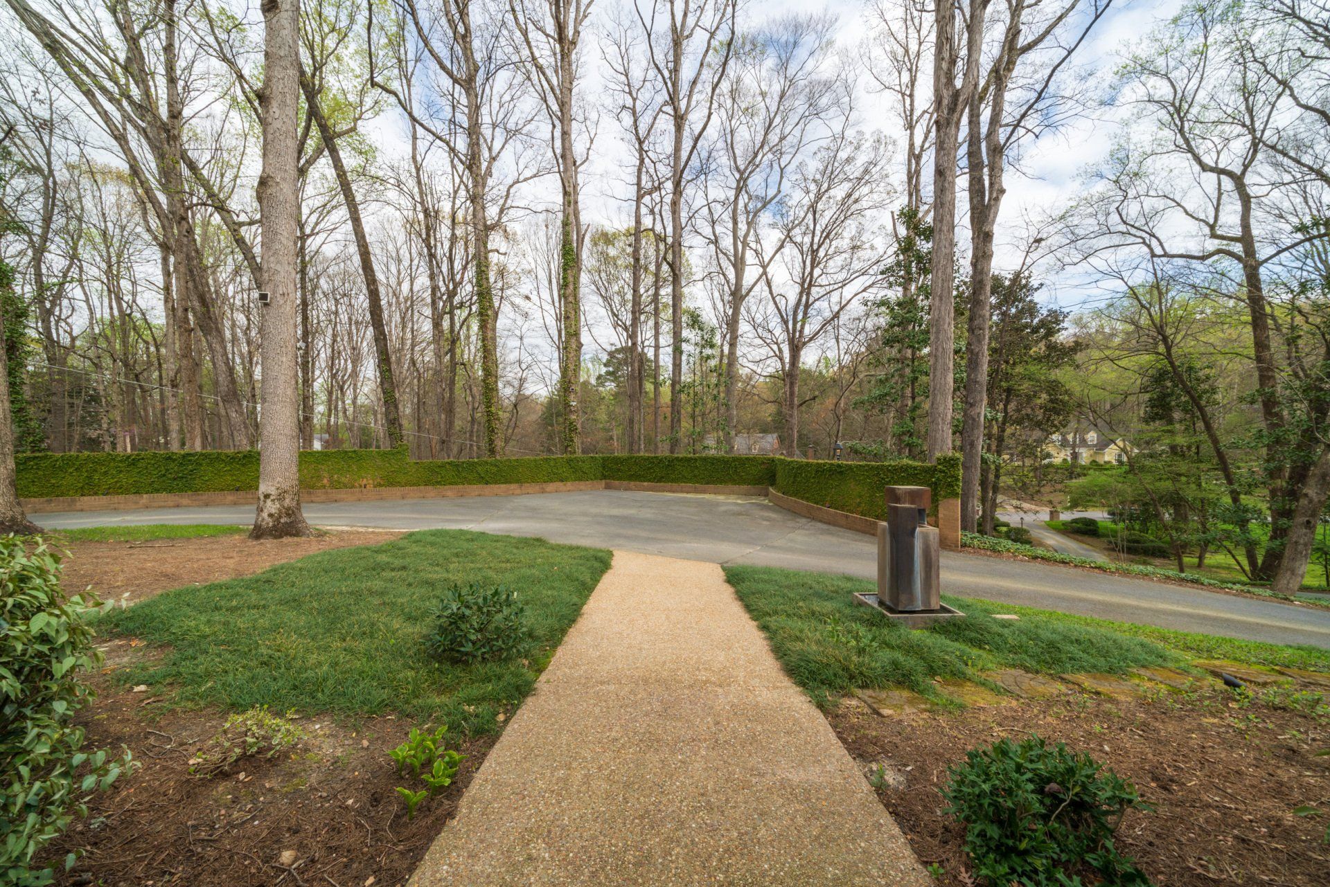 A gravel path leading to a parking lot surrounded by trees.