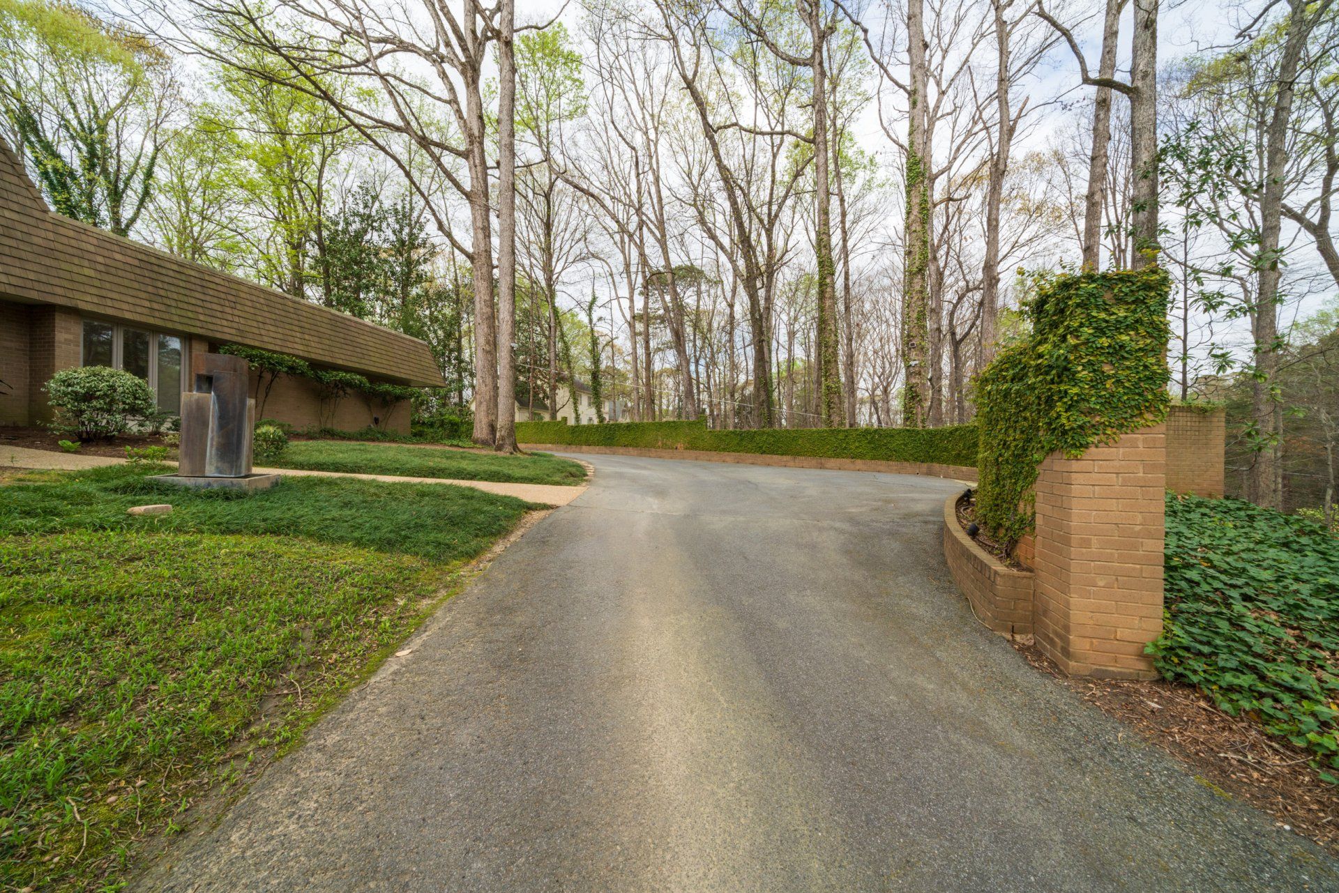 A driveway leading to a house surrounded by trees.