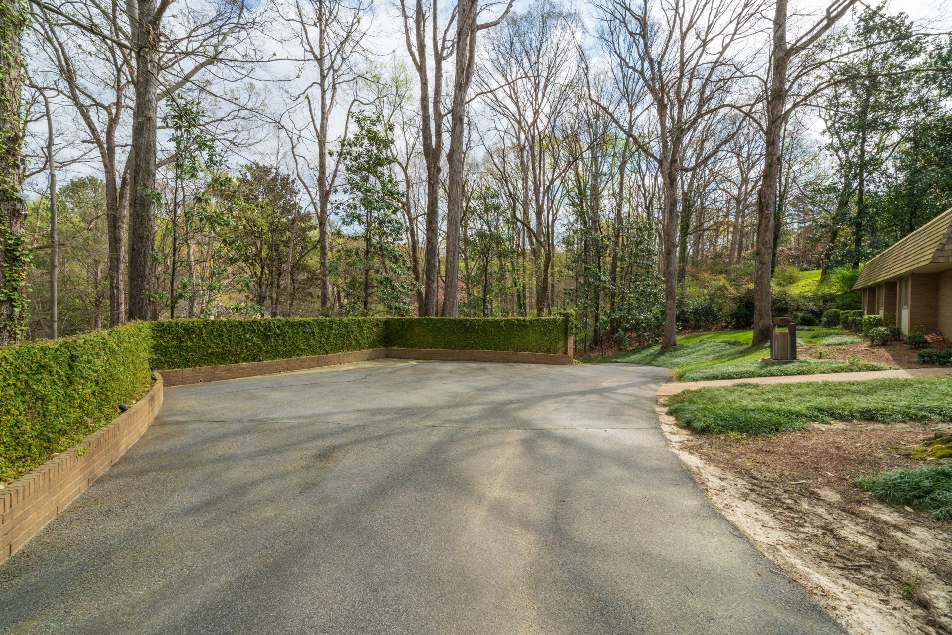 A driveway leading to a house surrounded by trees and bushes.