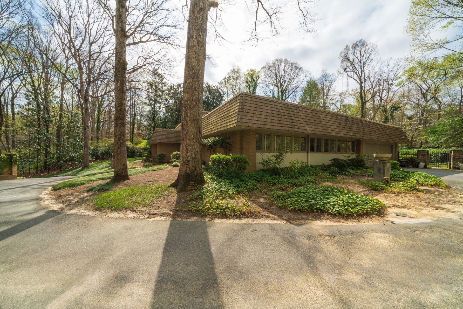 A house is sitting on the side of a road in the middle of a forest.
