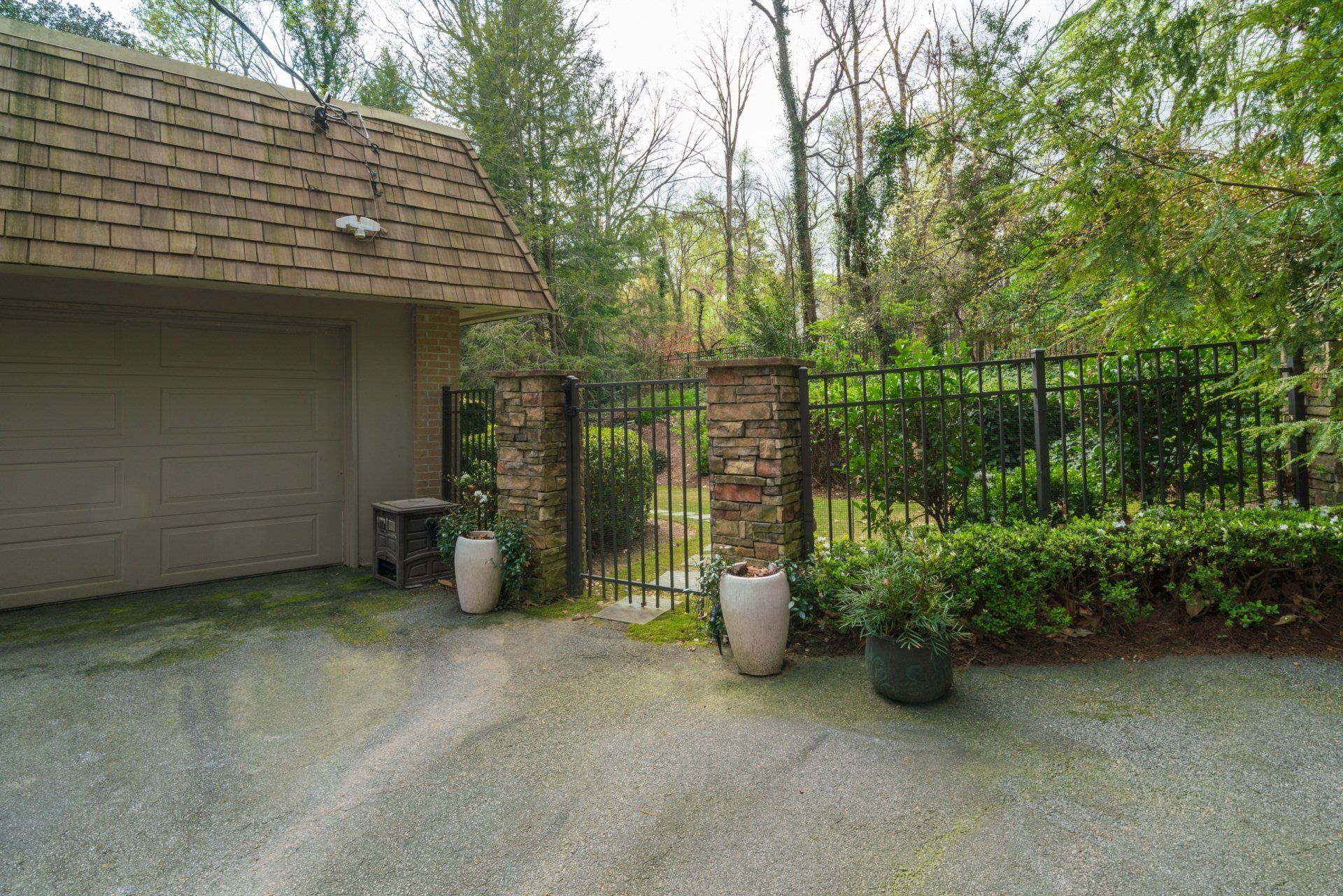 A garage with a fence and potted plants in front of it.