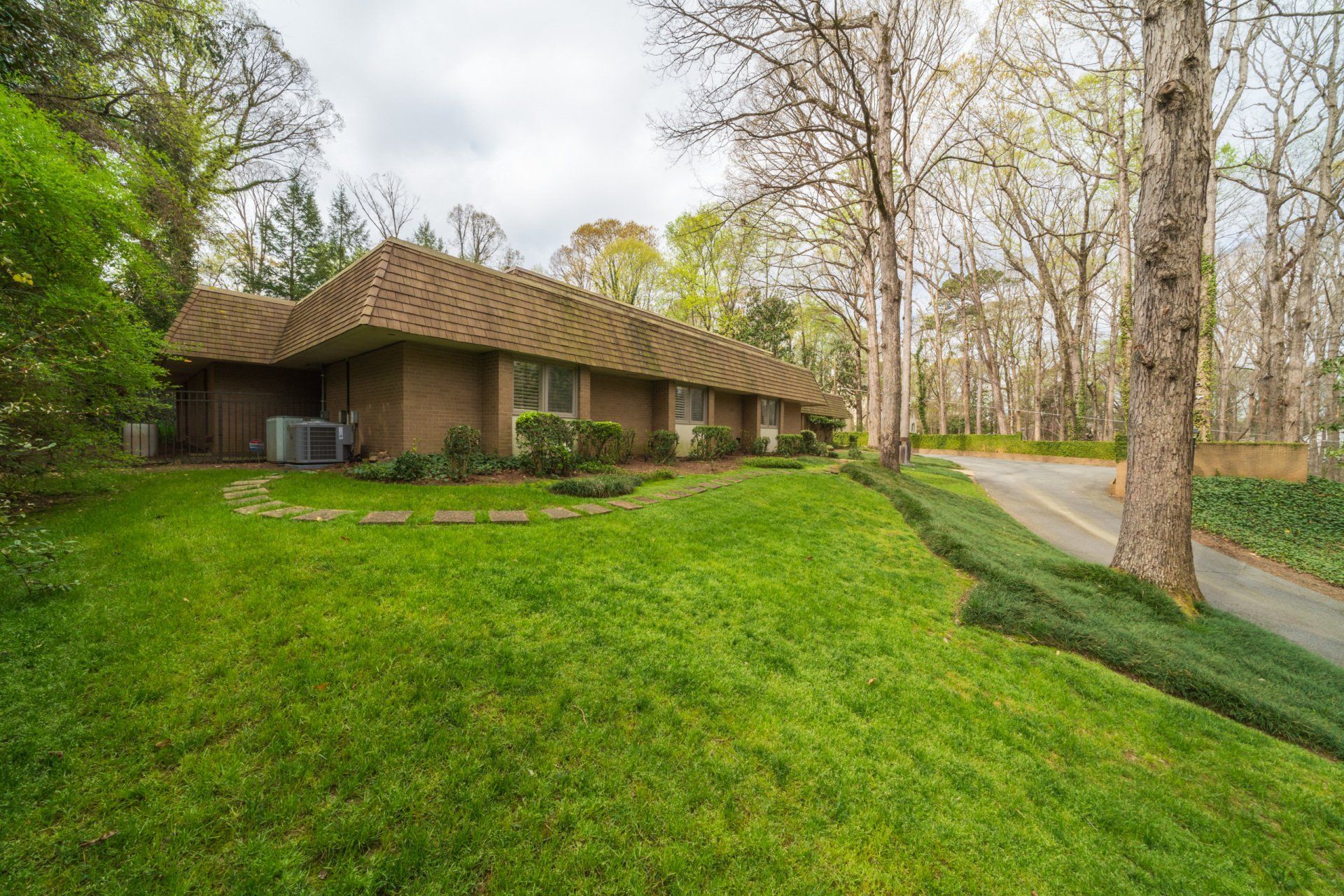 A large brick house with a lush green lawn and trees in the background.