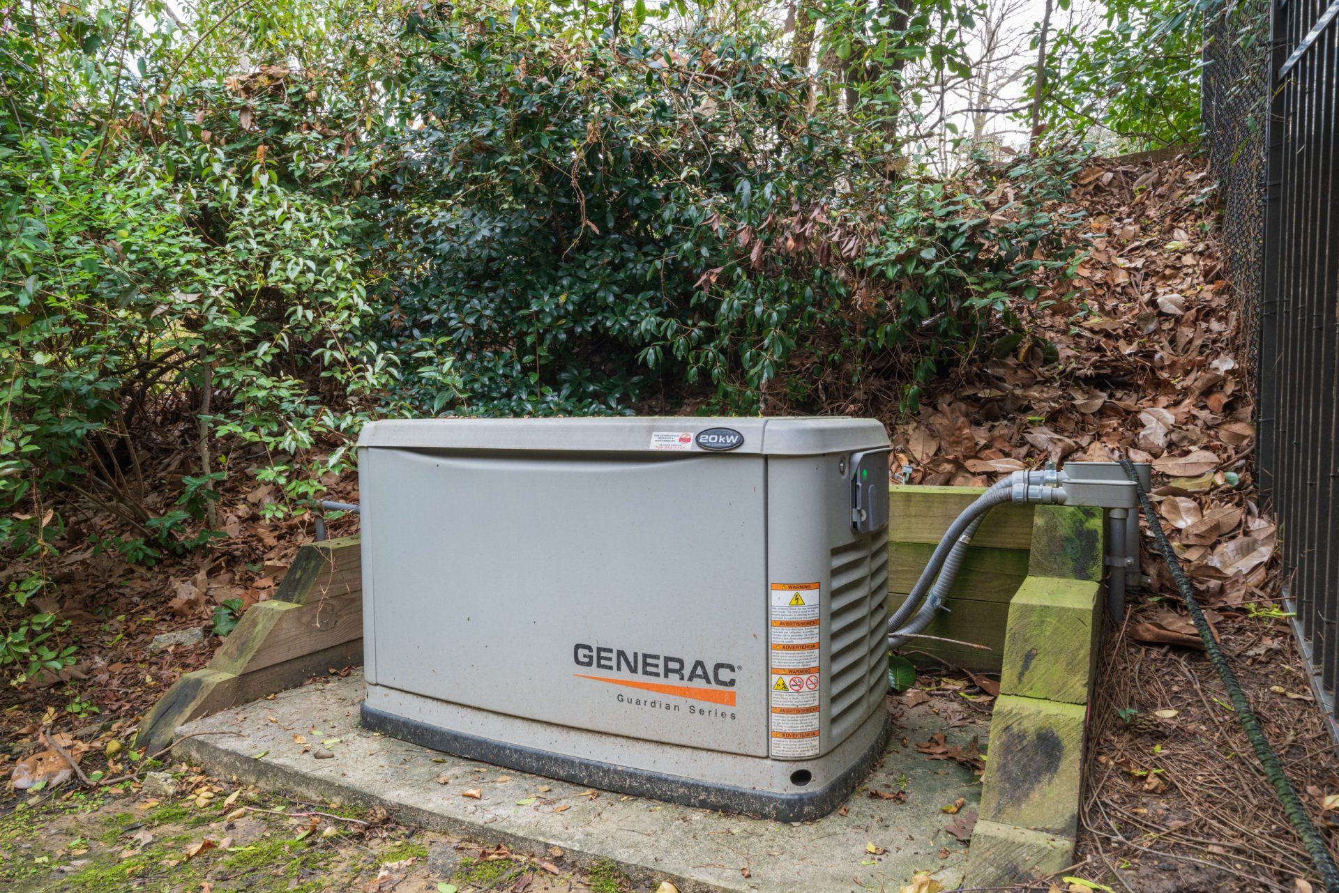 A generator is sitting on top of a concrete block in a backyard.
