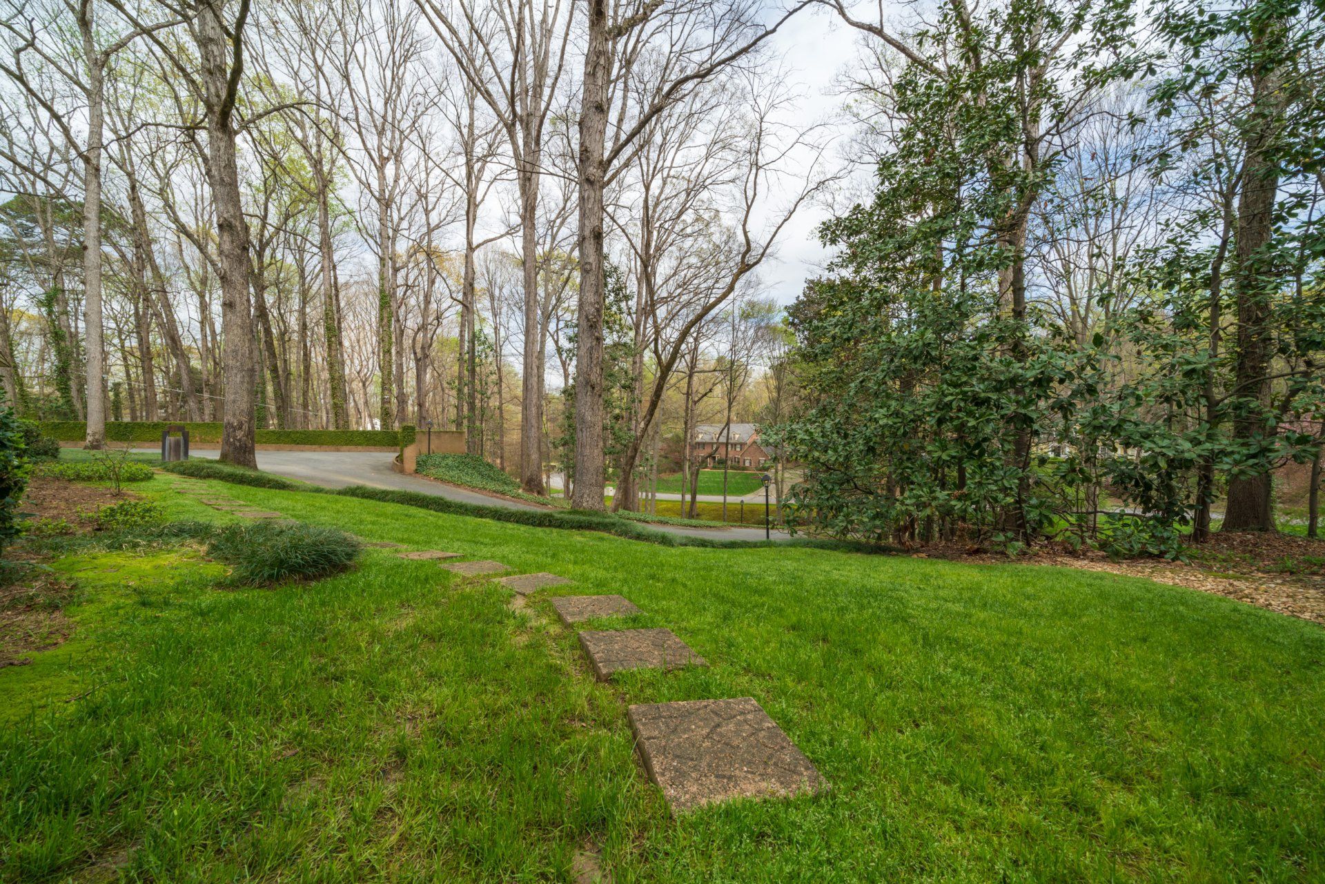 A lush green lawn surrounded by trees and a path.