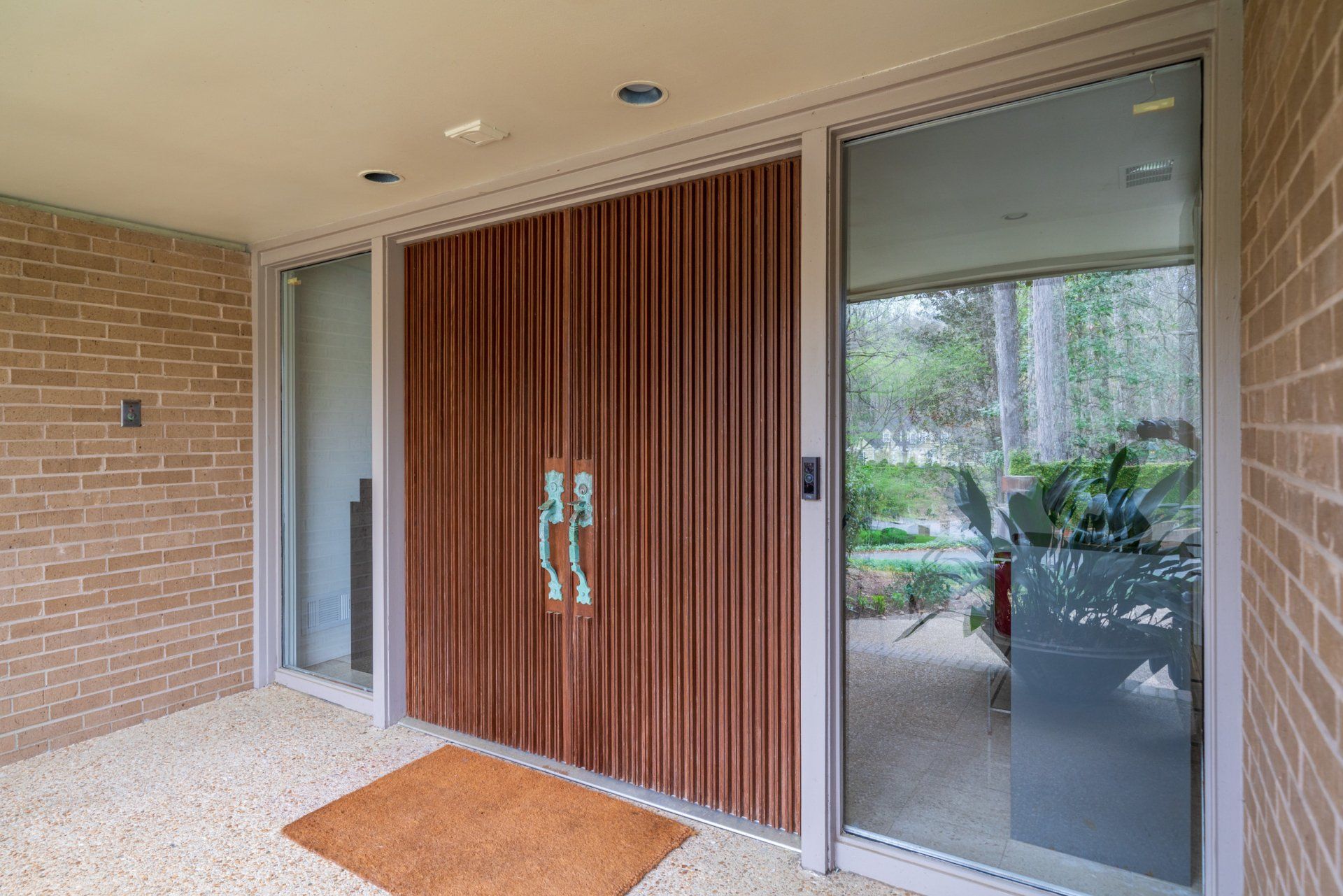 The front door of a house with a wooden door and a door mat.