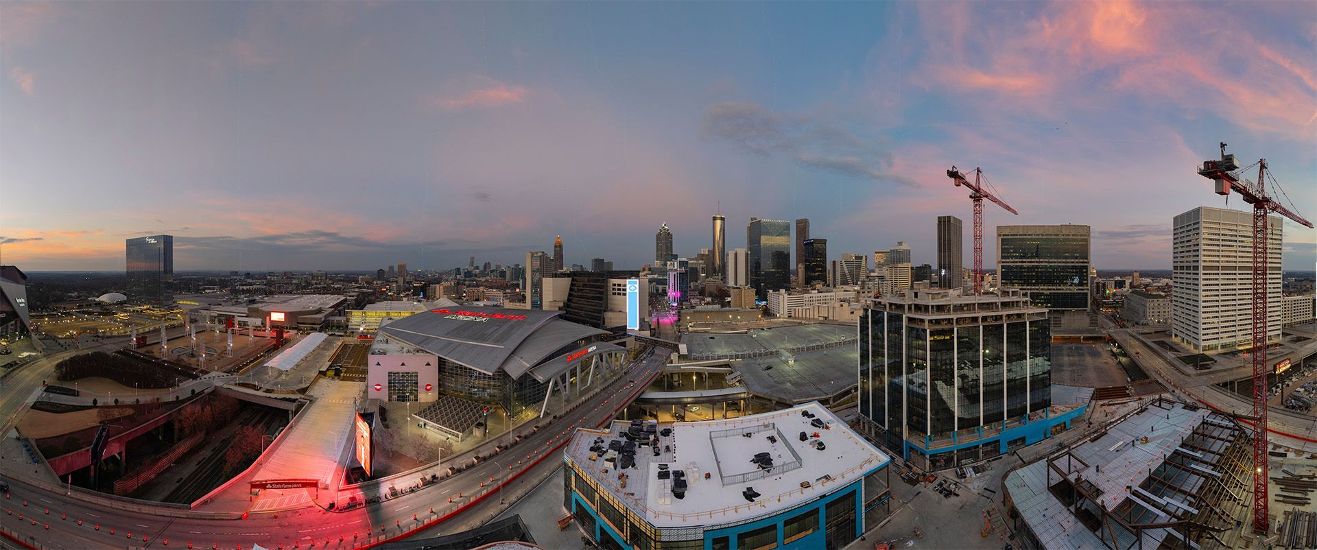 Aerial view of Centennial Yards in Atlanta, GA at dusk with construction cranes and buildings under construction.