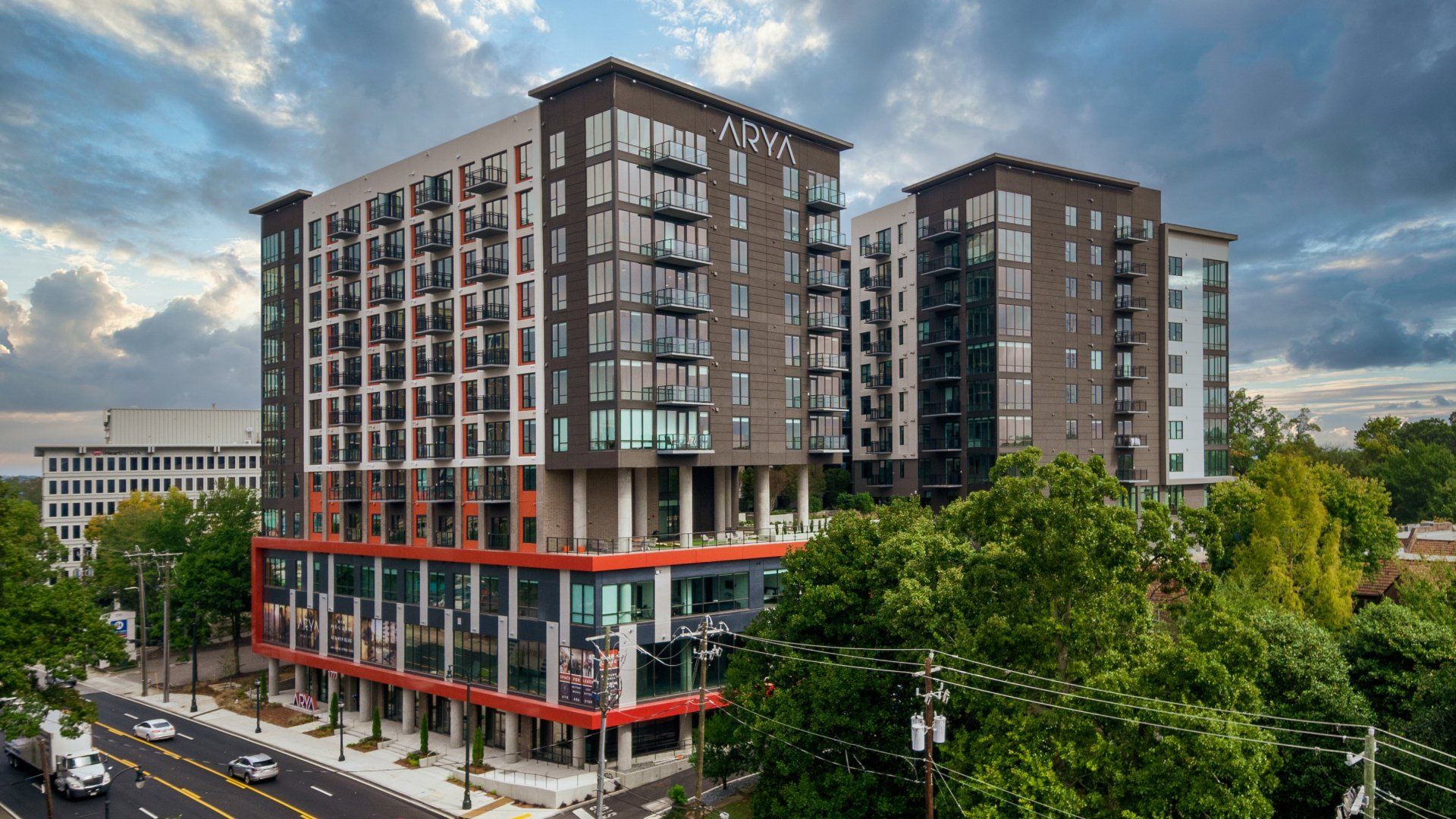 An aerial view of a large apartment building surrounded by trees and a street.