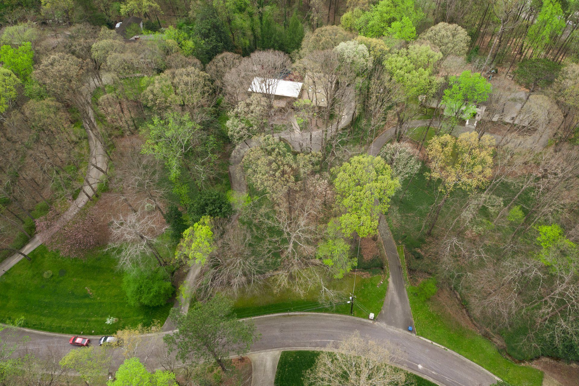 An aerial view of a house in the middle of a forest surrounded by trees.