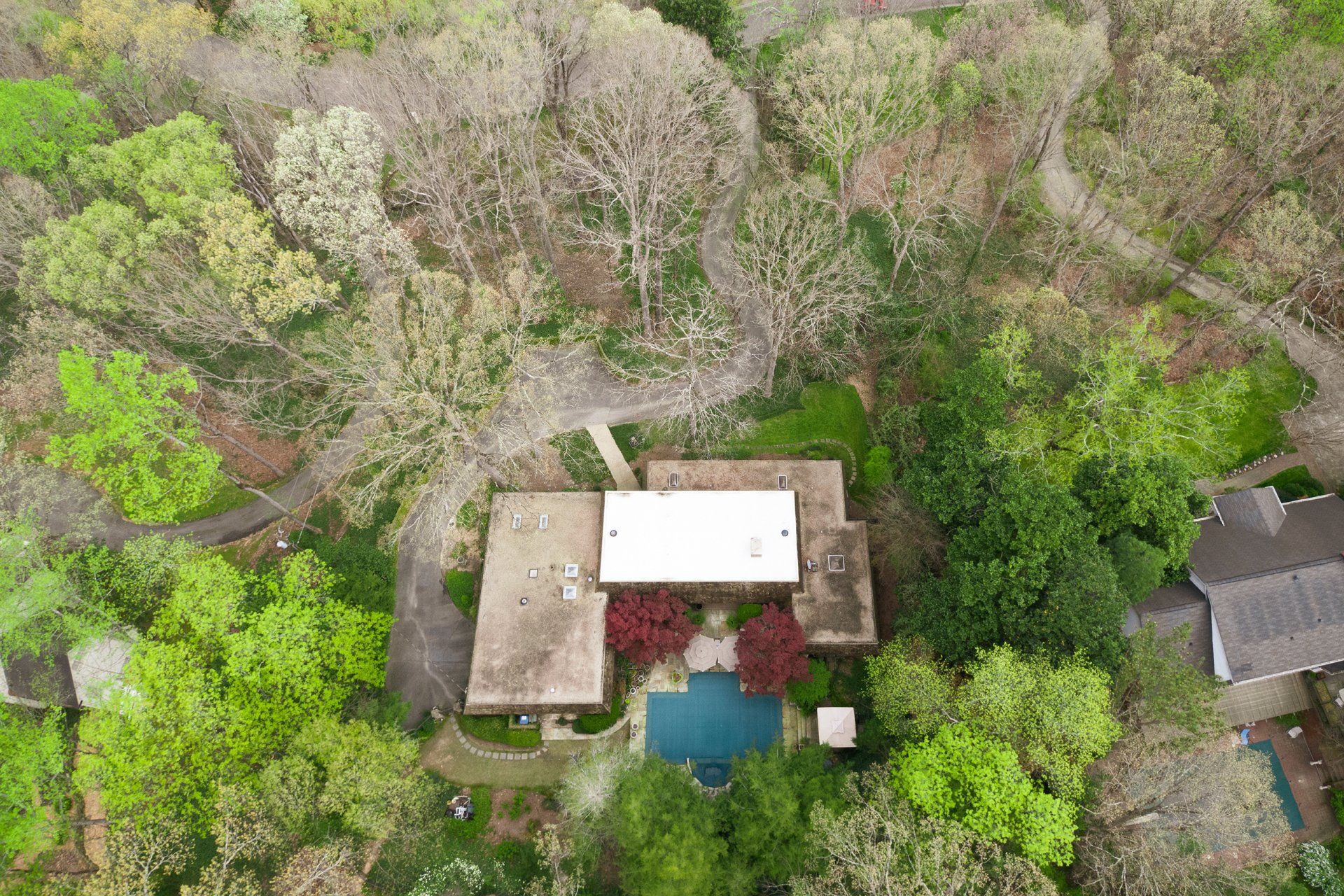An aerial view of a house surrounded by trees and a pool.