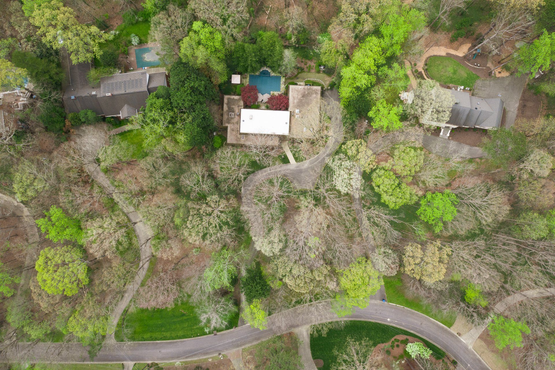 An aerial view of a house in the middle of a forest surrounded by trees.