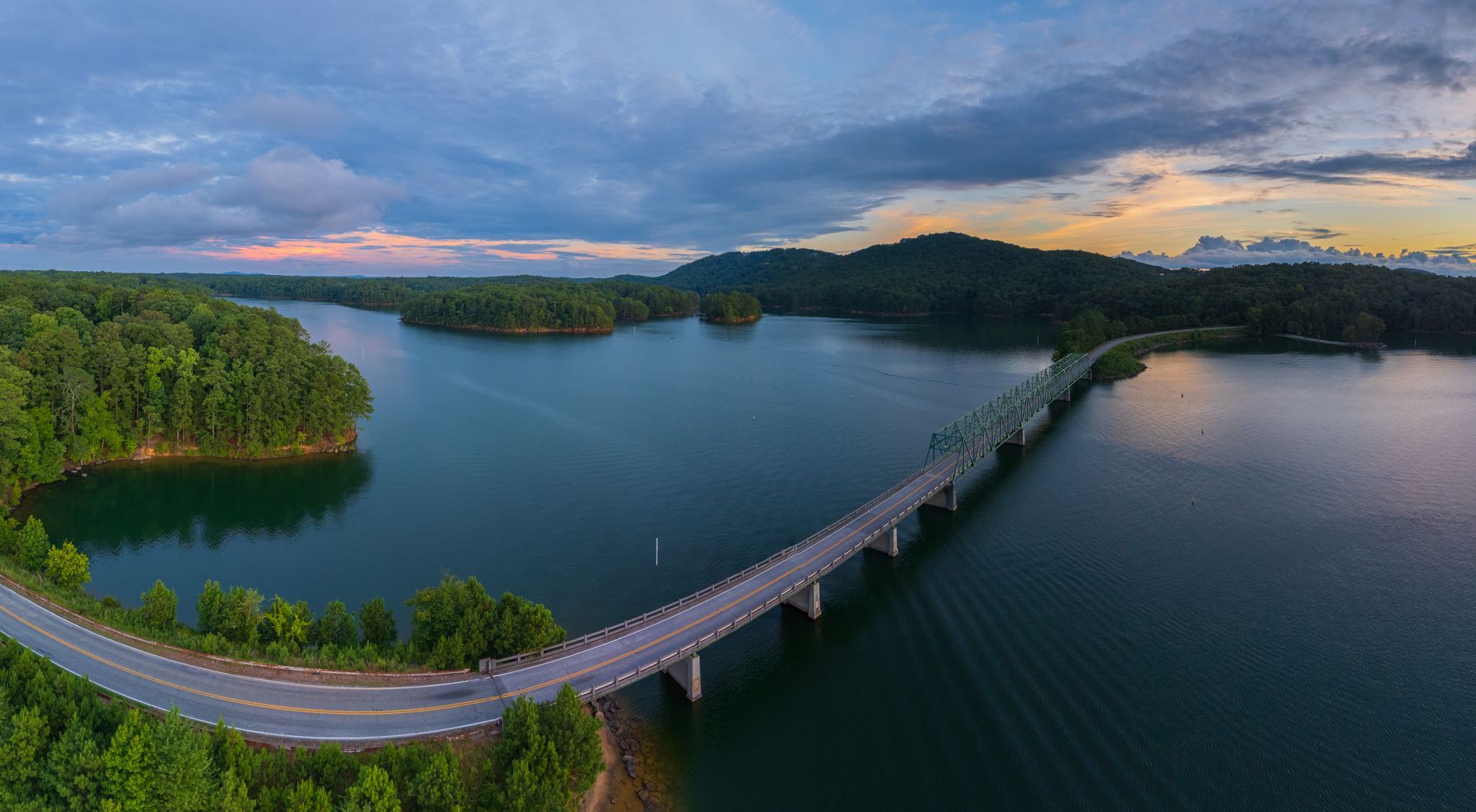 An aerial view of a bridge over a Lake Allatoona at Red Top Mountain State Park surrounded by trees.