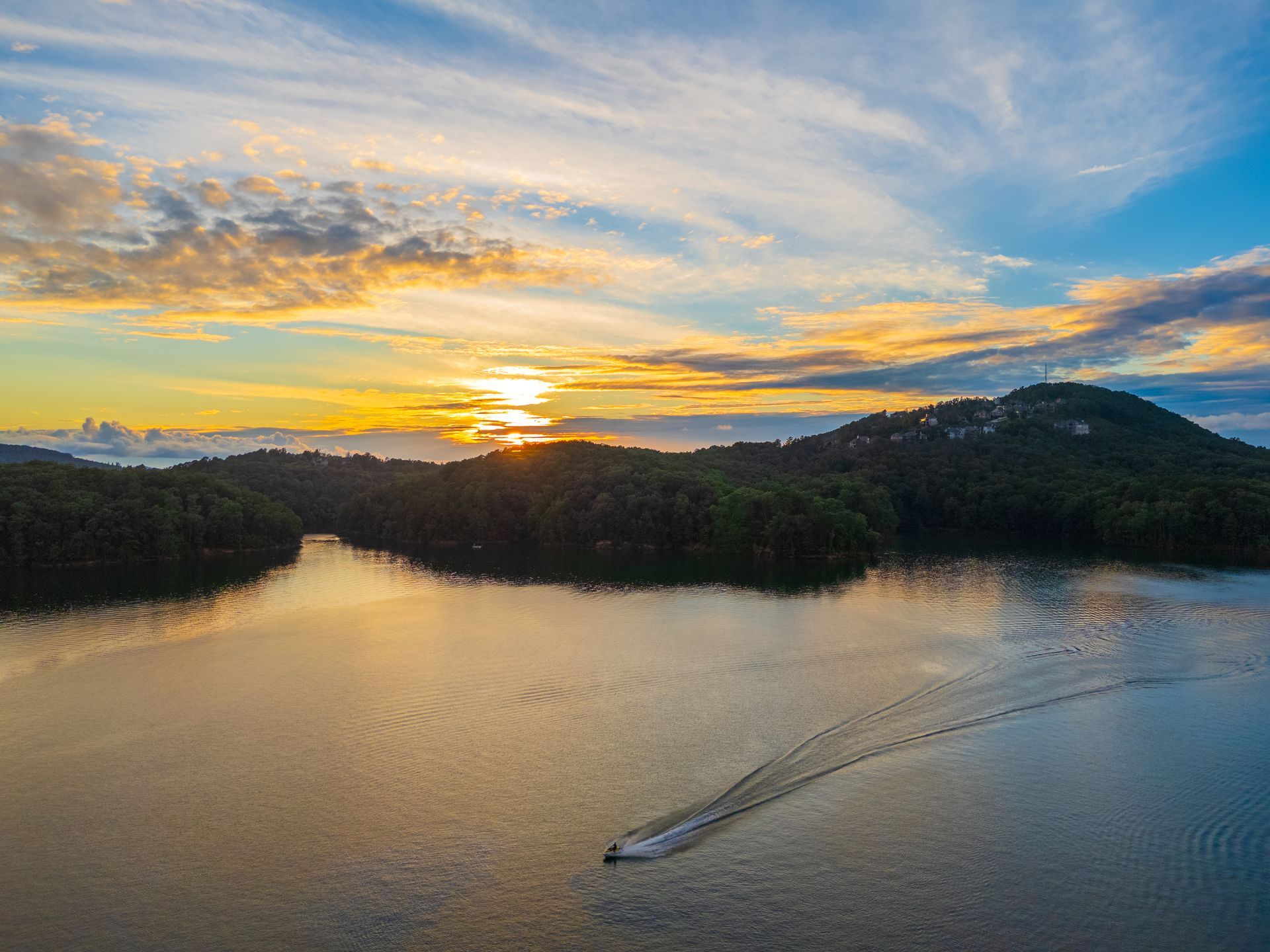 An aerial view of Lake Allatoona at Red Top Mountain State Park at sunset with a boat in the water.